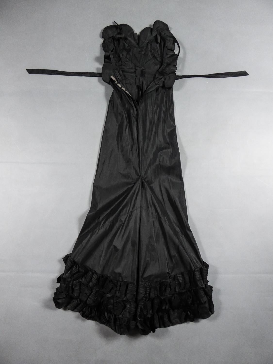 Circa 1935
France

Amazing evening dress with train in black silk taffeta from a Parisian wardrobe mainly made up of Jean-Charles Worth Haute Couture Dress Circa 1935. Generous long dress with V-shaped backless and thin straps. Buttoned at the back