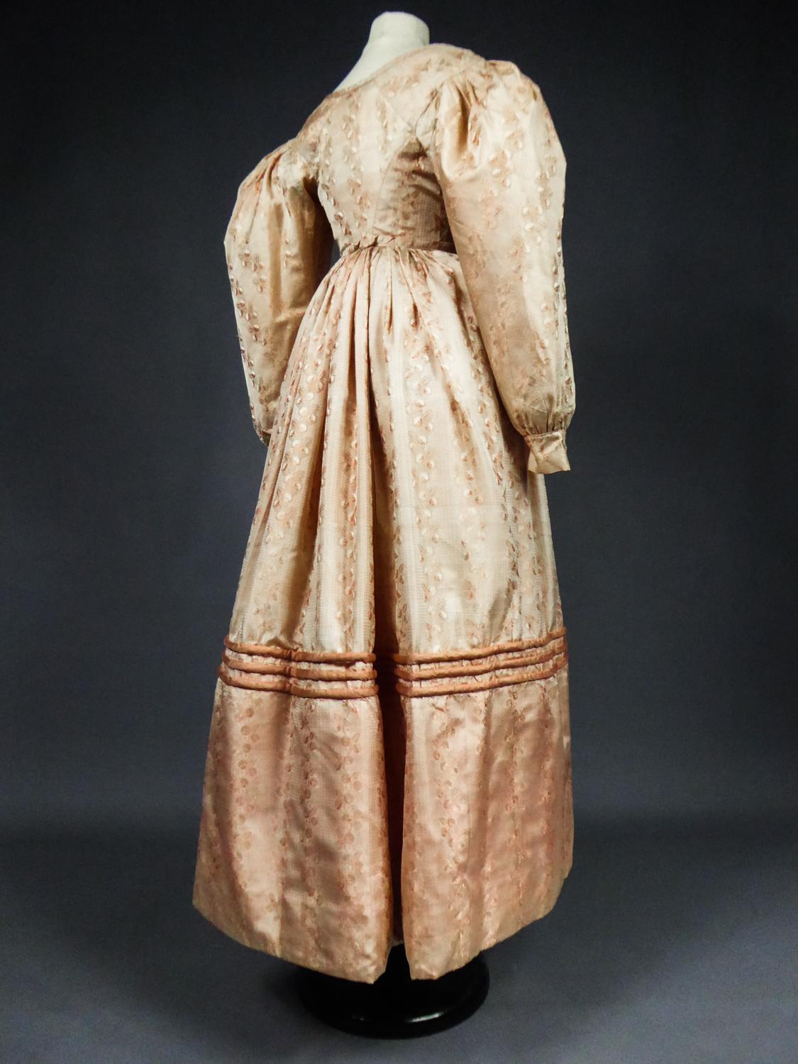 Um 1825
Frankreich Charles X Periode

Modisches Ballkleid aus der Zeit der frühen romantischen Silhouette mit überschnittenen Schultern und langen Ärmeln aus kleinem Hammel. Leichter Damast aus blassrosa Seidenstoff mit Girlanden aus stilisierten