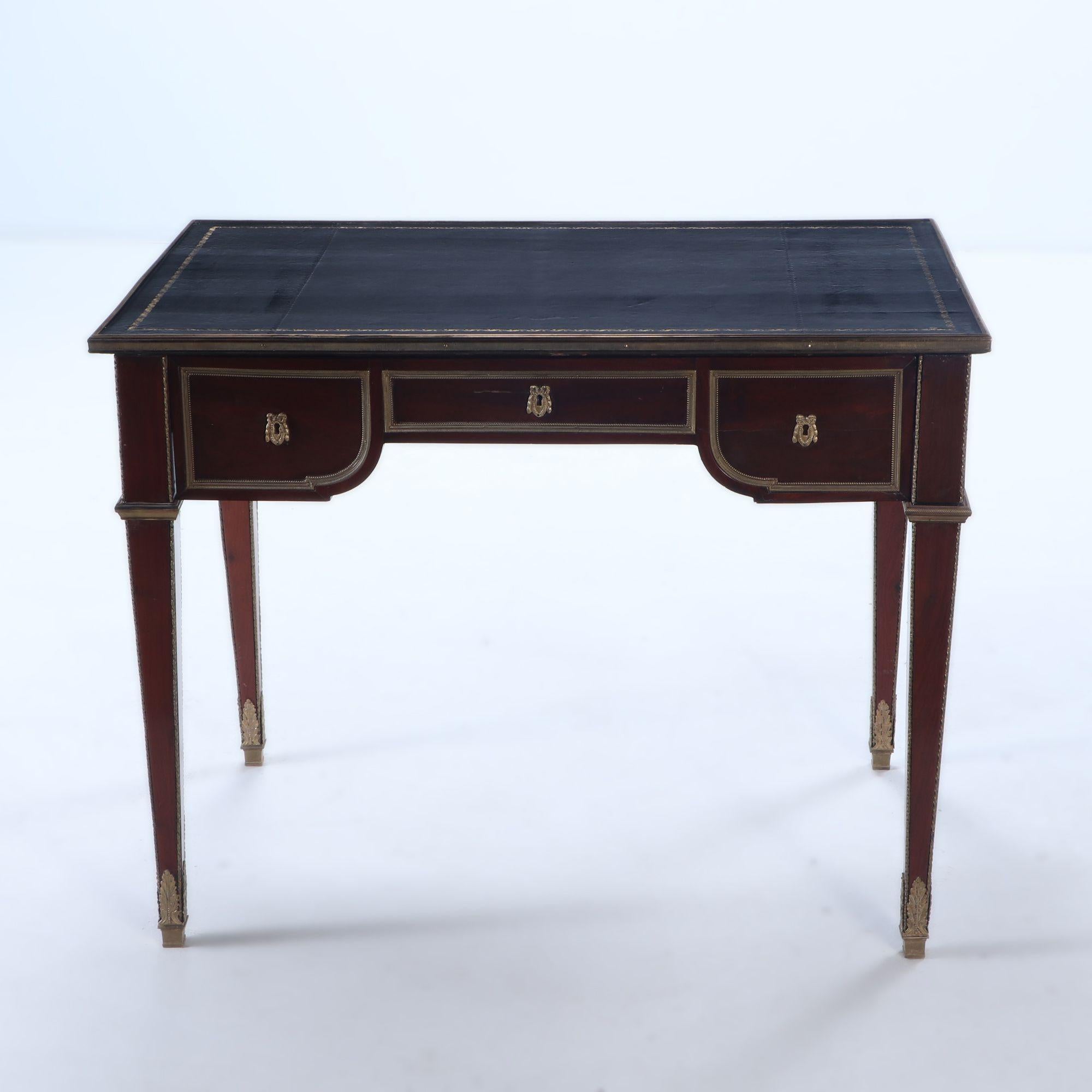 A Louis XVI style French three drawer mahogany bureau plat desk having extensive bronze decoration, finished rear and gilt embossed leather top circa 1930.
Kneehole Dimensions: 26