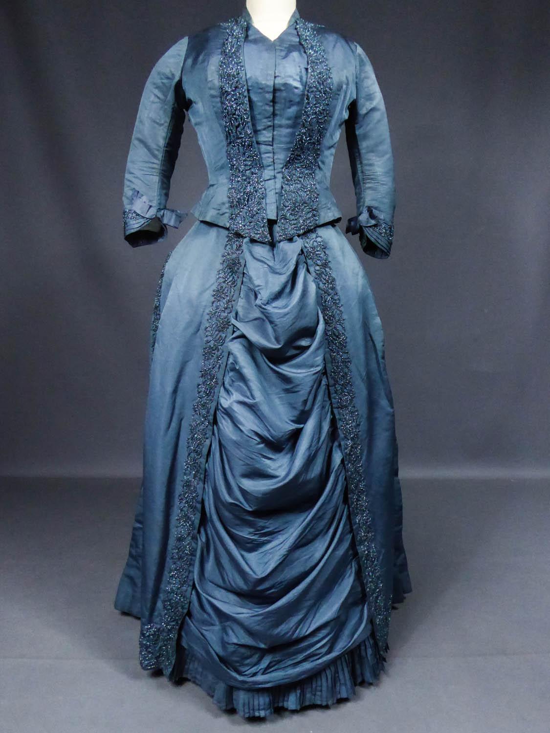 Circa 1880/1890
France Lyon

Beautiful turned over reception or dinner dress with a train by Madame Seine in Lyon around 1885. Bodice and skirt in fluted Prussian blue silk ottoman embellished with applied embroidery in river of iridescent blue