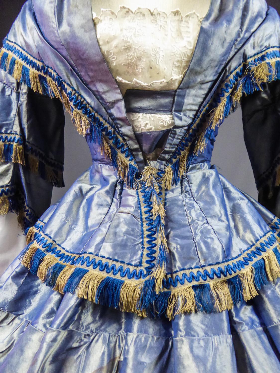 Circa 1855
France

French Day dress with bodice and round crinoline skirt in changing and noising taffeta dating from the beginning of the Second French Empire. Boned bodice with integrated pleated capelet and large basques with taffeta knot on the