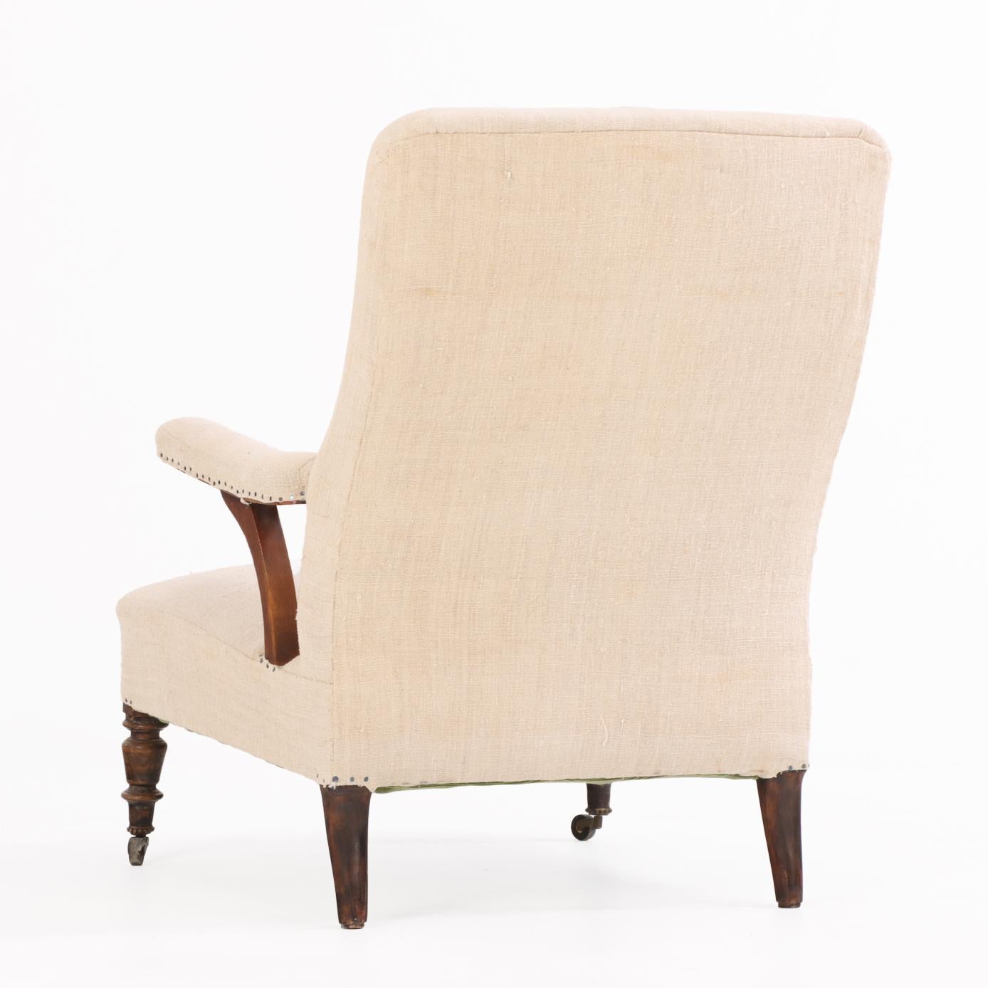 The chair presents an S-shaped back with straight crest rail, open arms supported by curving floating supports, and turned front legs complemented by subtly flared back legs. Recently upholstered in a neutral-toned fabric, the seat and backrest are
