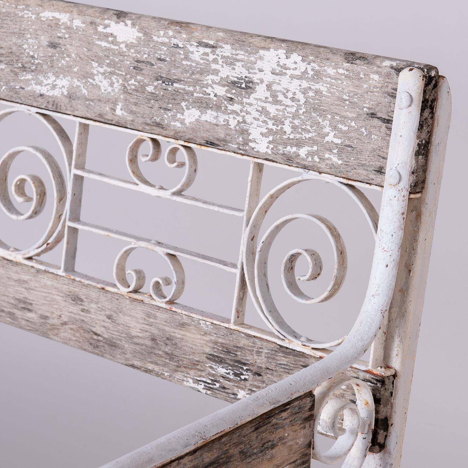 Featuring a classic combination of wood and wrought iron in a decorative pattern, this bench came from a hotel in Vichy, France, a town known for its luxurious spas and healing waters. The wood is nicely aged with traces of white paint remaining,