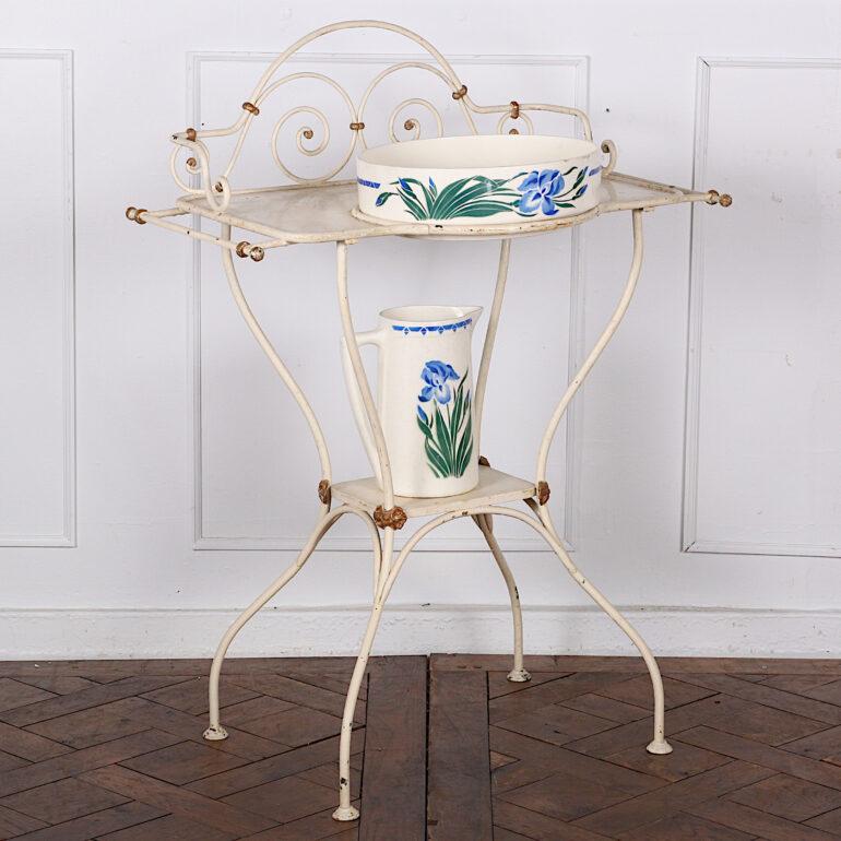 A French painted wrought iron washstand with an Art Nouveau-influenced sinuous design to the legs and scrolled back splash. Original ceramic bowl and jug with iris motif. 

 