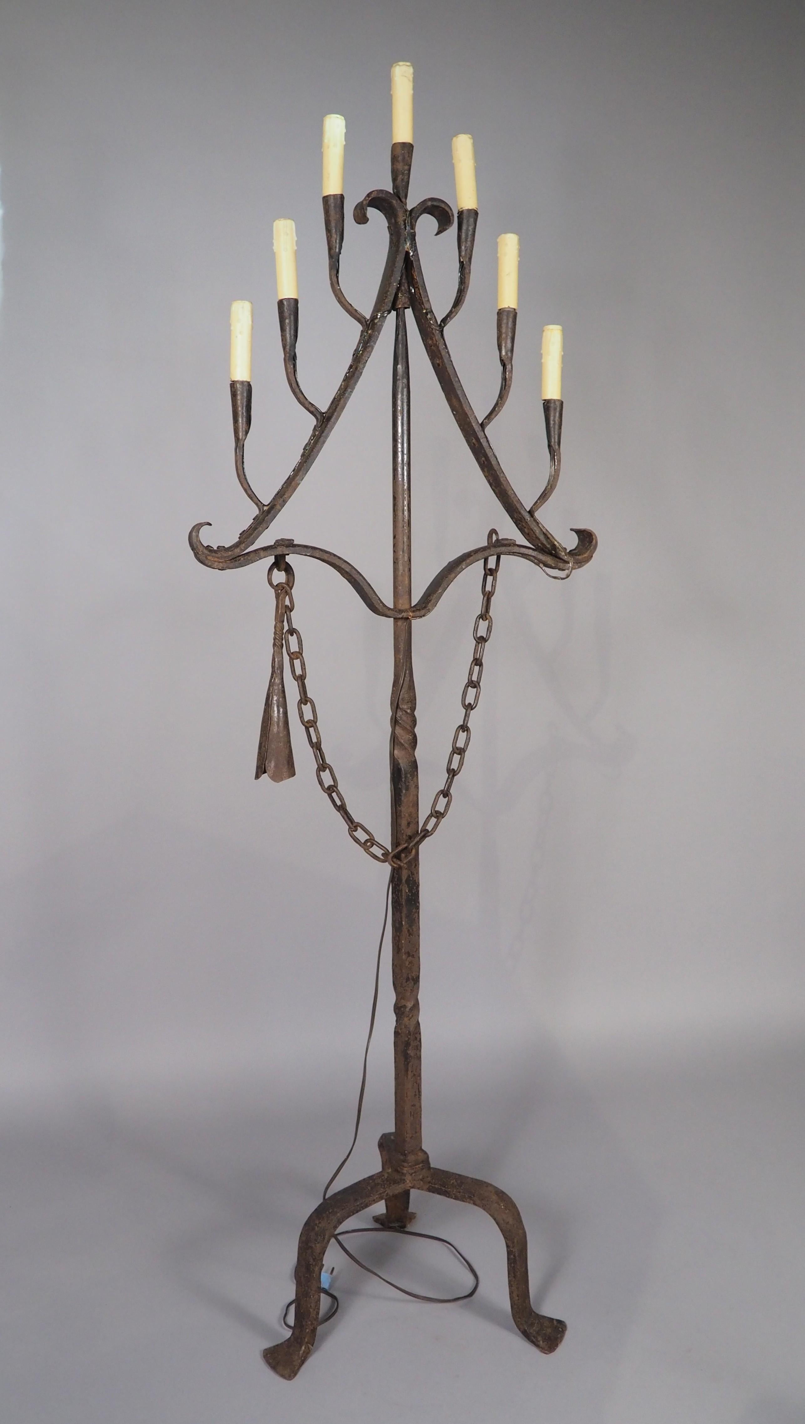 More information coming soon…

The seven lights on this French wrought iron floor candelabra are arranged in a triangular pattern, with the center arm rising above the other six.  The original candle snuffer is intact, permanently affixed by a long