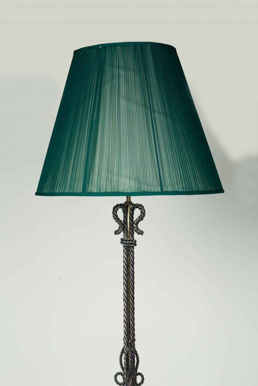 The wrought iron columnar support simulating rope, resting on the scrolling feet; fitted with two bulb sockets; with a vintage green silk shade.