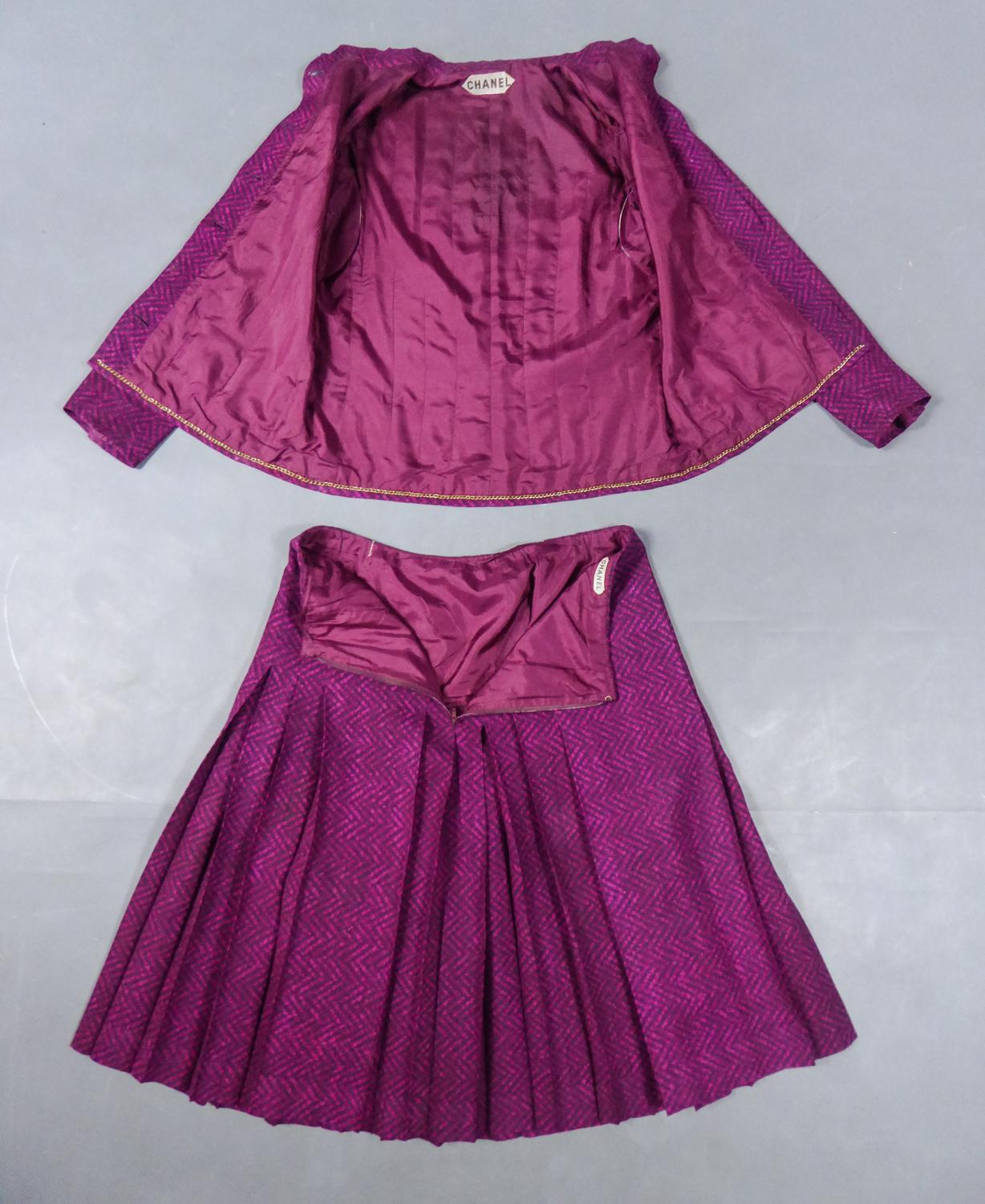Circa 1980
France

Rare ensemble jupe et veste Chanel Haute Couture pour l'été datant du début des années 80. Serge de soie imprimée d'un motif zigzag fushchia sur fond bordeaux. Veste avec col mandarin et chaîne en laiton cousue à l'intérieur,