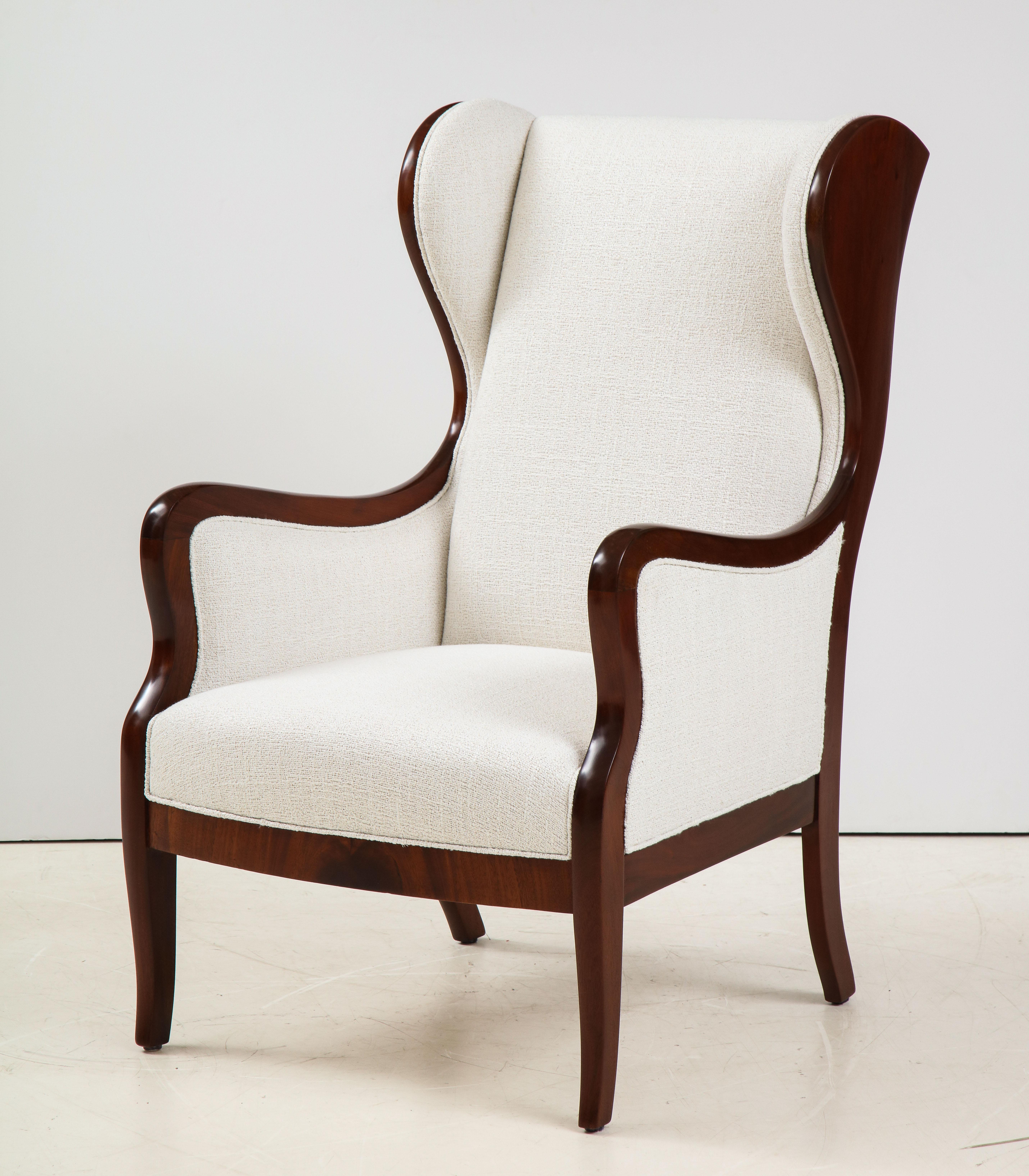 A Frits Henningsen mahogany high backed wing chair, Circa 1940-50, with strong and graceful lines exhibiting the confidence of Copenhagen cabinet maker, Frits Henningsen. Re-French polished and fully re-upholstered in an off-white Boucle fabric.

 