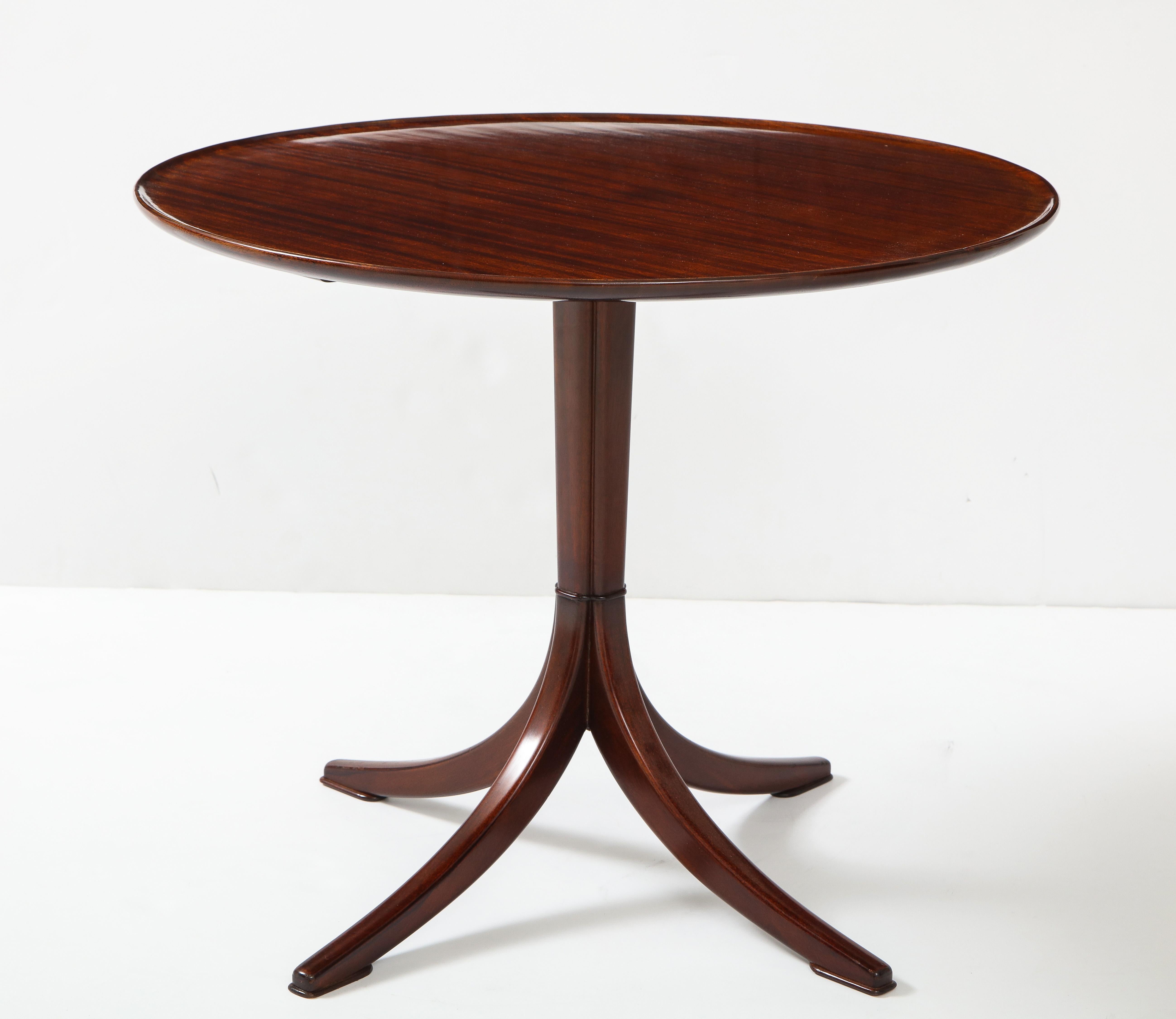 Scandinavian Modern Frits Henningsen rich mahogany side table, circa 1940s, with a circular edged top raised on a clustered stem with four downswept legs.
  