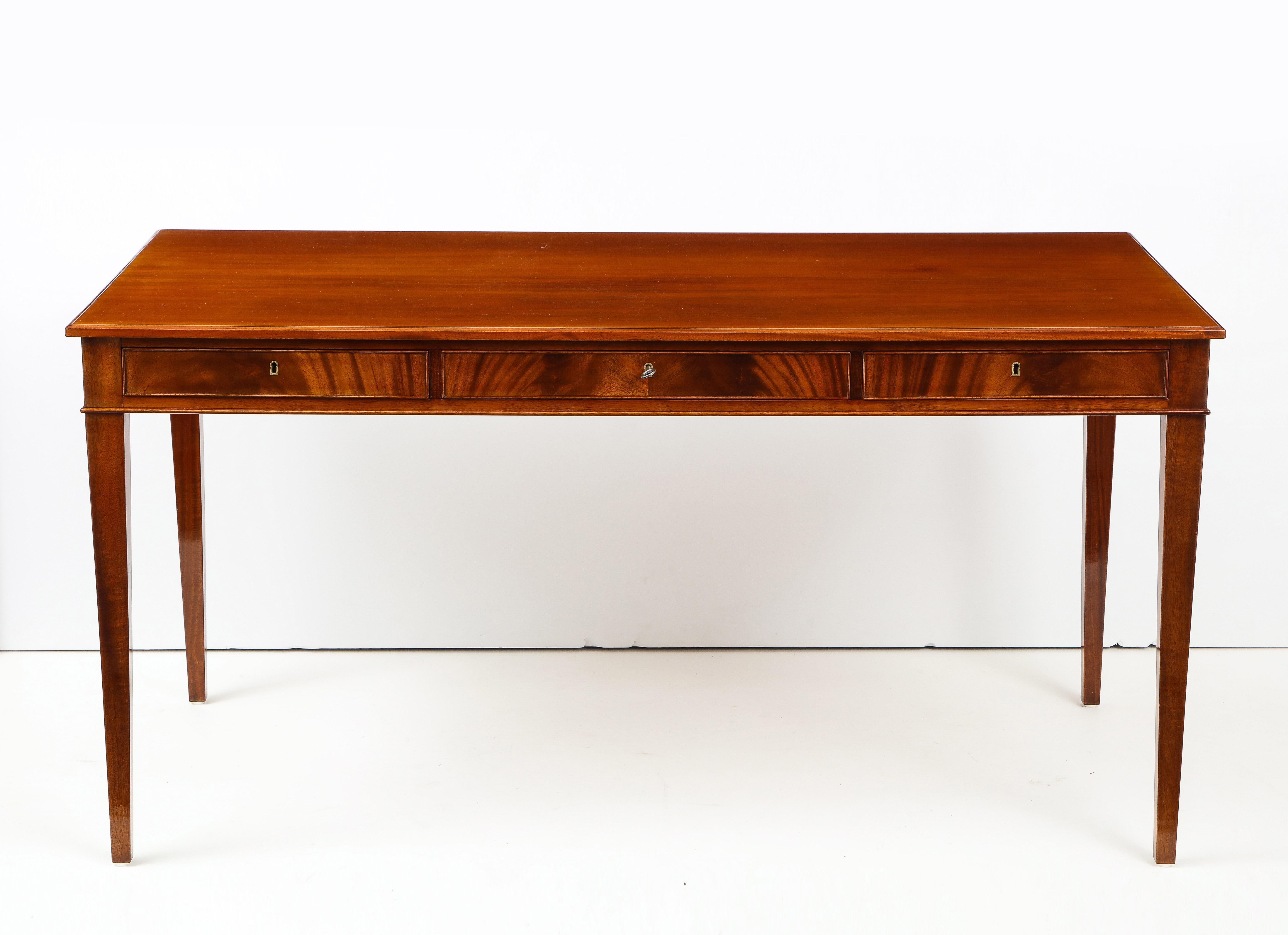 A Danish mahogany writing table by Frits Henningsen, furniture designer and cabinet maker (1889-1965). This desk is a Classic example of Henningsen's elegant clean lines and use of quality woods with perfect balanced craftsmanship. A rectangular top