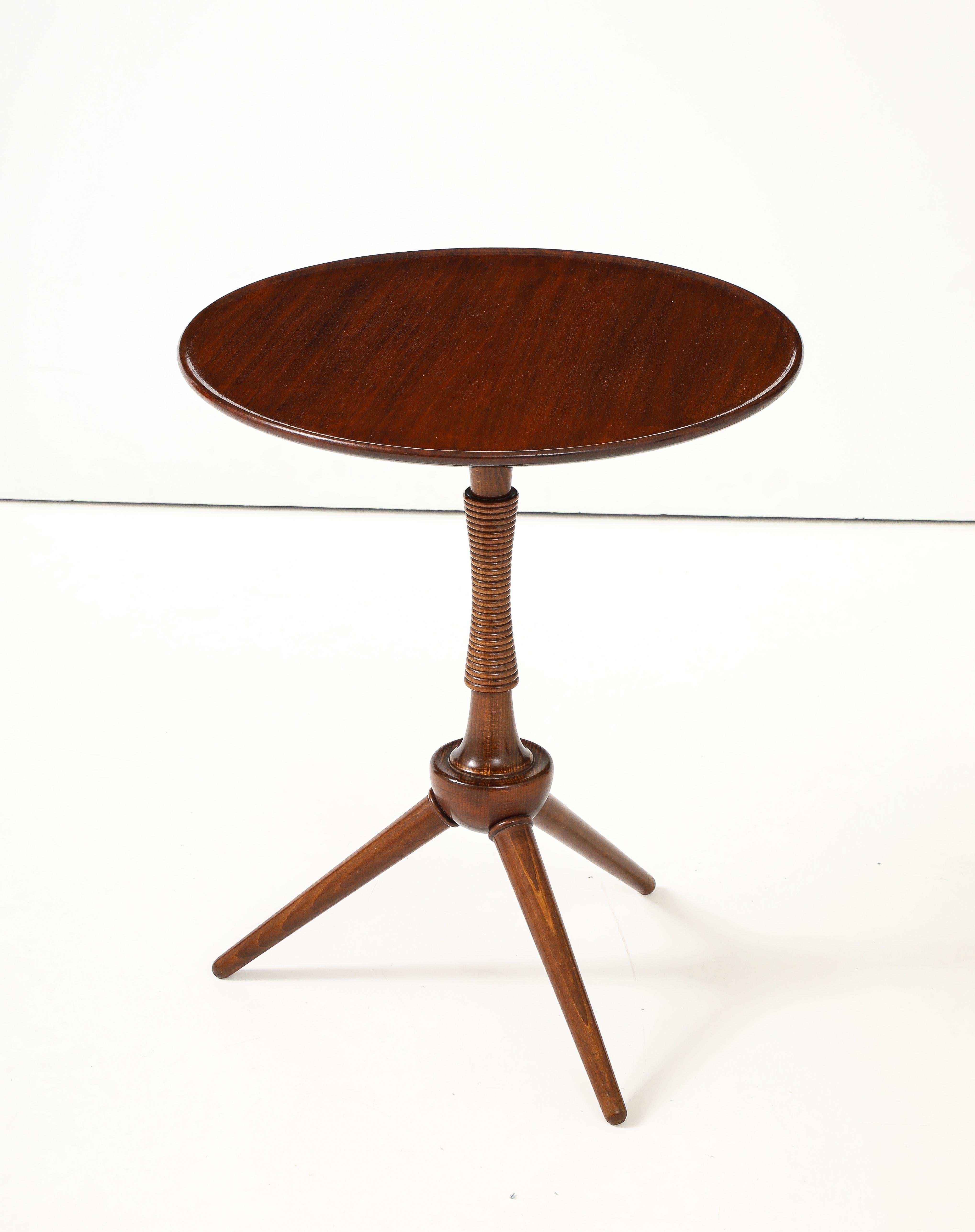 Tavolo tripode in mogano danese, anni '40 circa, disegnato e prodotto da Frits Henningsen, con un piano circolare a bugna sollevato da un gambo parzialmente tornito, affusolato e divaricato, che termina con tre gambe circolari affusolate.