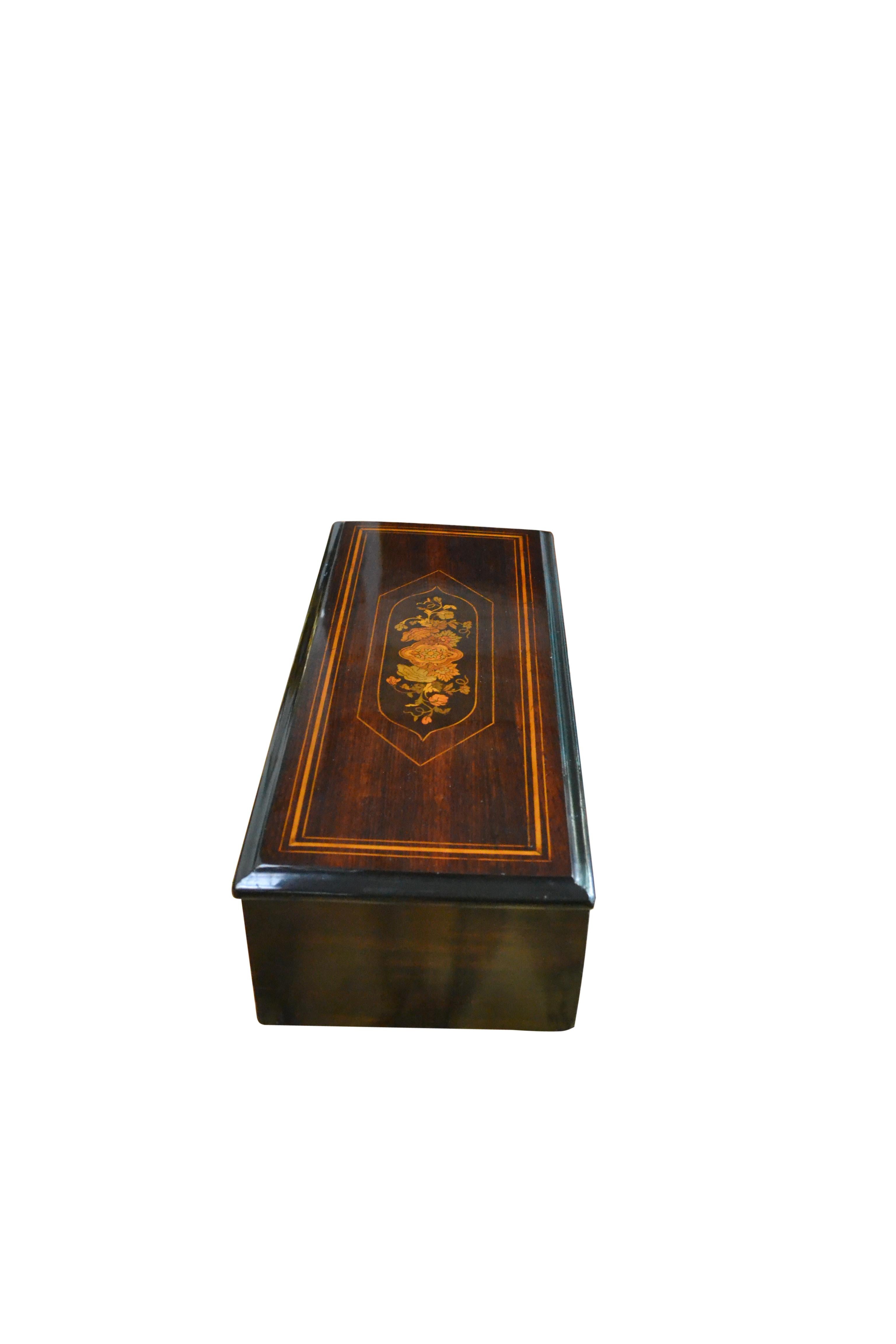 Boîte à musique suisse à cylindre entièrement restaurée et en état de marche, enfermée dans un coffret en bois fruitier poli, avec un médaillon central floral incrusté sur le couvercle à charnière.  qui s'ouvre pour révéler le mouvement mécanique