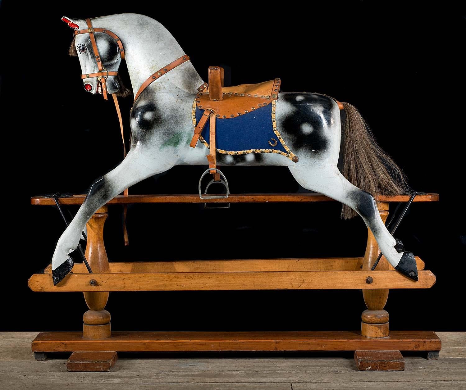 A beautiful, fully restored Victorian rocking horse complete with a studded leather saddle, blue saddle blanket and leather reins and stirrups. The handsome horse securely rocks on it's pine and beechwood cradle.
English, late 19th century.