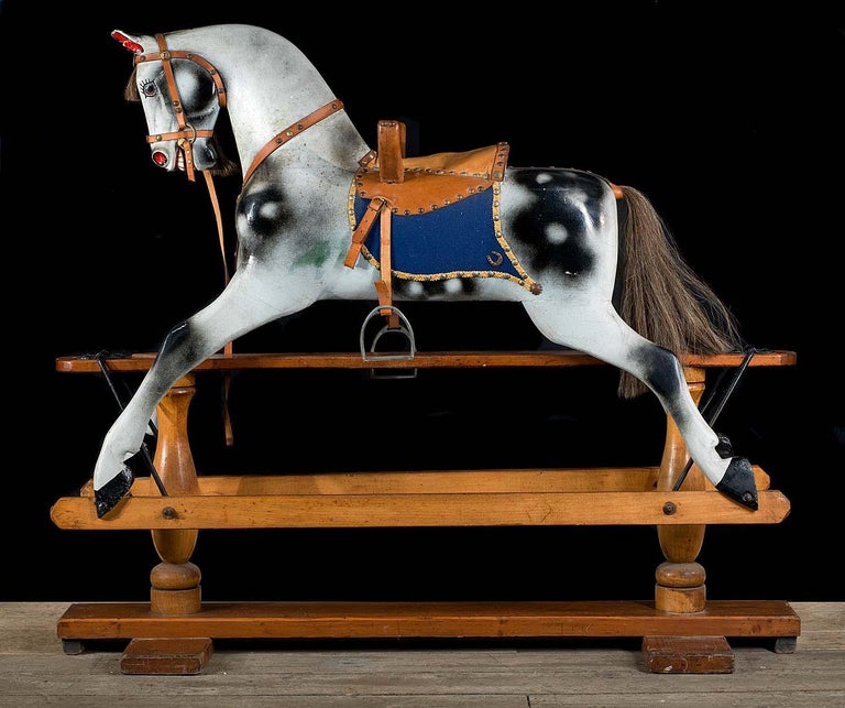 A beautiful, fully restored Victorian rocking horse complete with a studded leather saddle, blue saddle blanket and leather reins and stirrups. The handsome horse securely rocks on it's pine and beechwood cradle.
English, late 19th century.