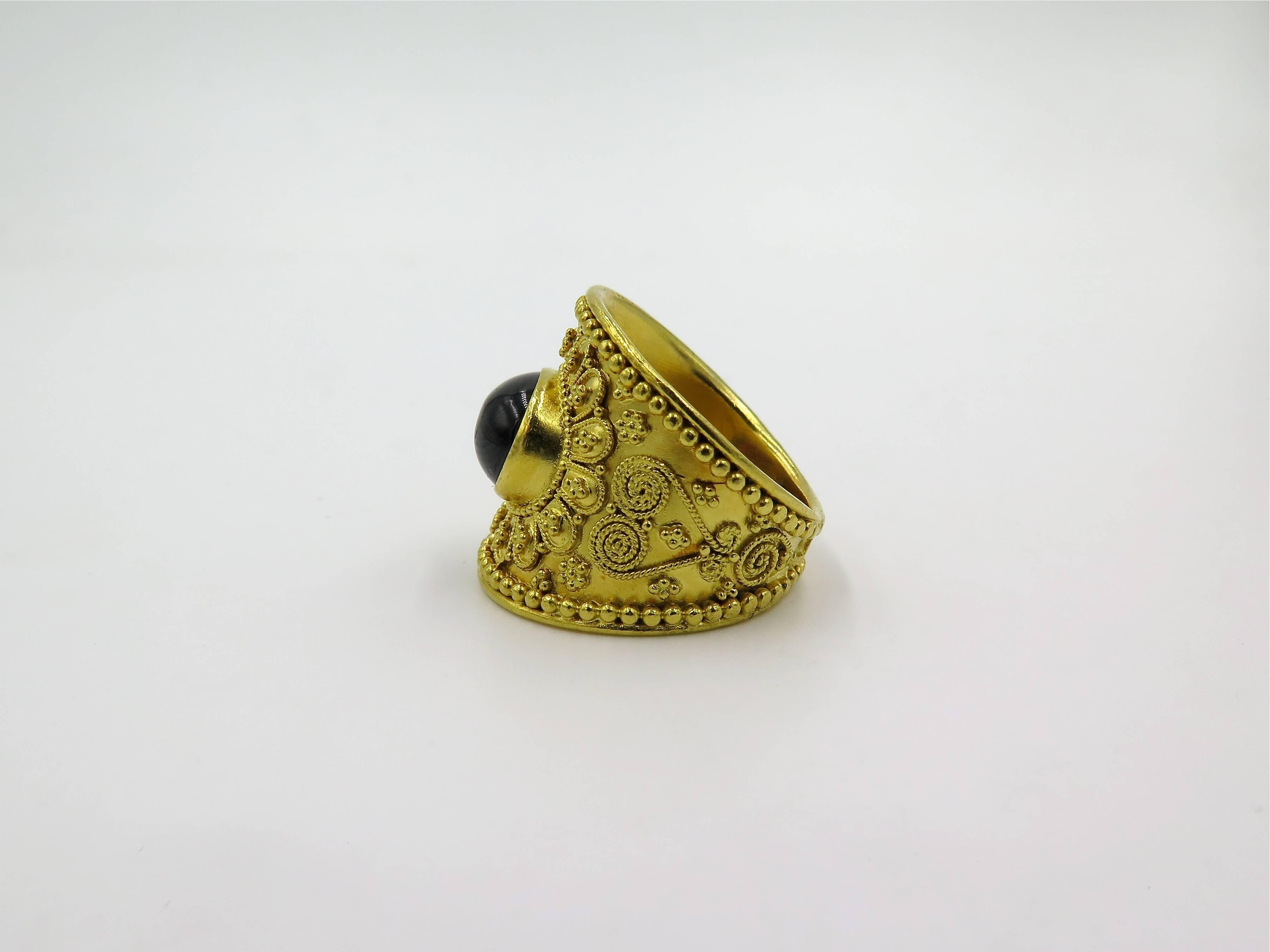 An 18 karat yellow gold and garnet ring.  Lalaounis.  Circa 1990. Designed as a tapered band, centering a cabochon garnet, enhanced by granulation.   Size 6 3/4, gross weight is approximately 11.5 grams. 