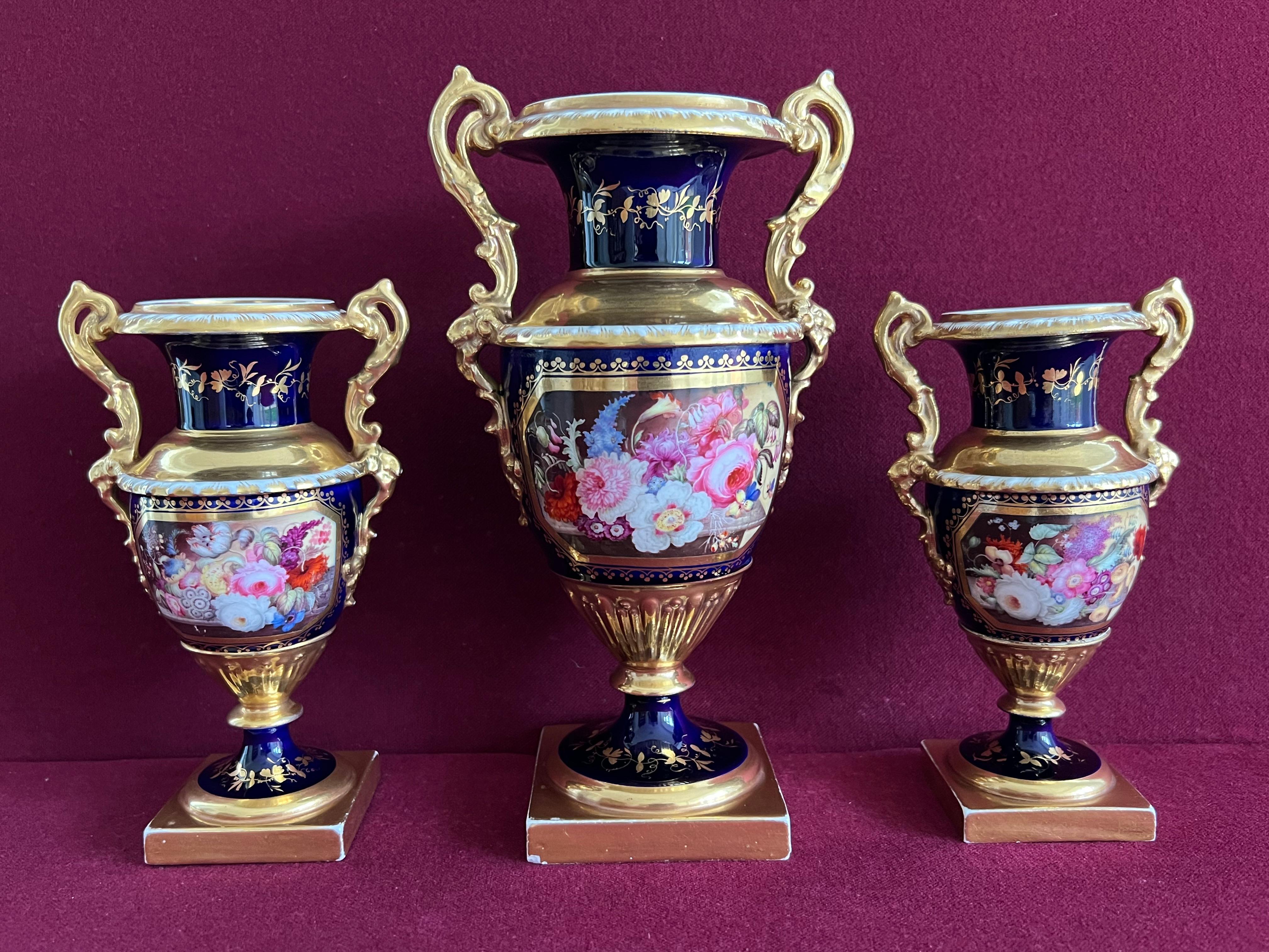 A Garniture of Minton Porcelain Vases decorated by Thomas Steele c1830. Each vase of 'Elgin' shape, finely decorated with a well executed panel of flowers on a marble table by Thomas Steel. Marks: + sign on a circle in gold.

Condition: A few small
