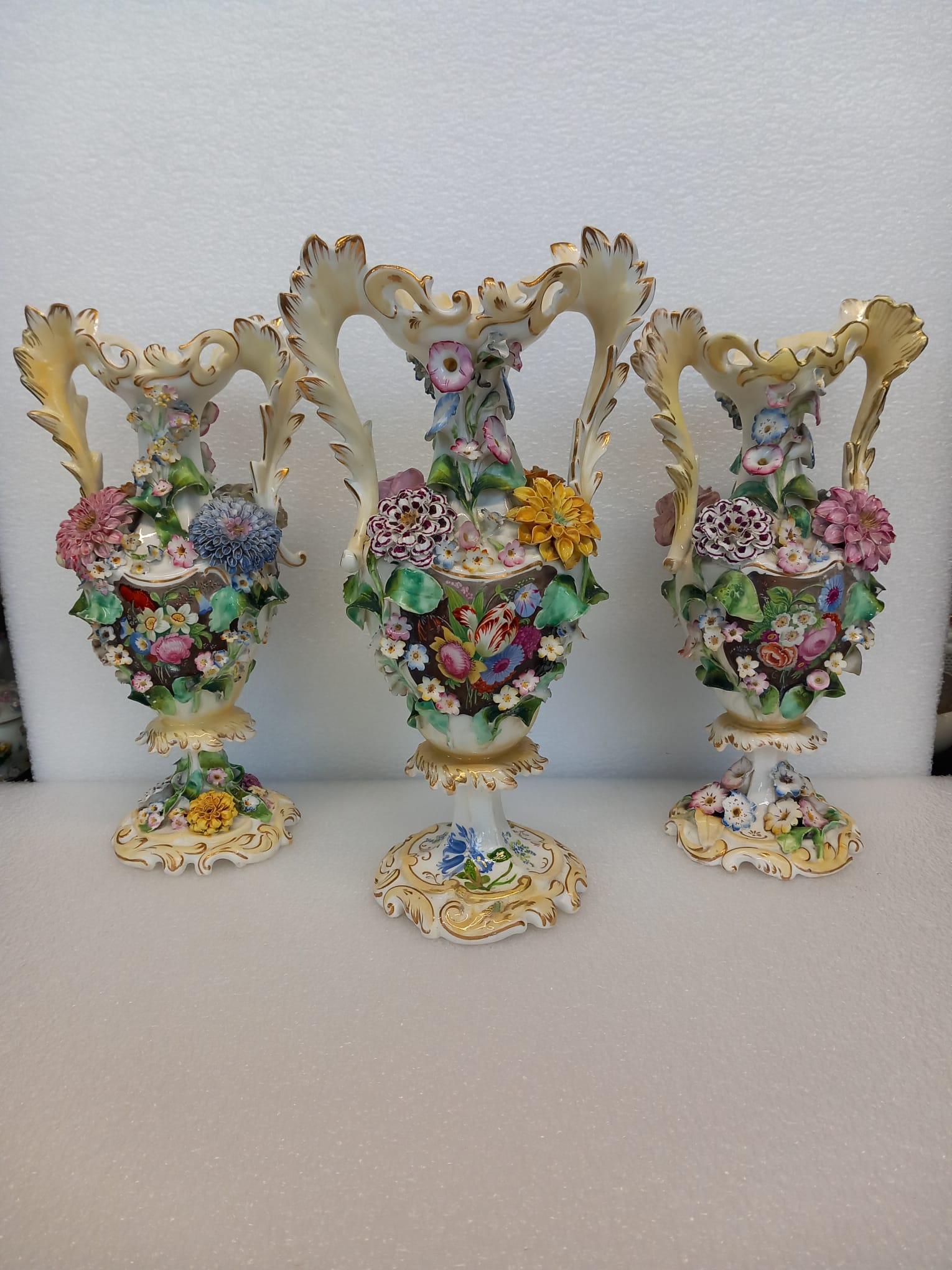 A garniture of three antique English porcelain vases, heavily decorated with hand made porcelain flowers and hand painted with wonderful flower cartouches in the Dutch style.
The porcelain is most likely to have been manufactured by John Ridgway as