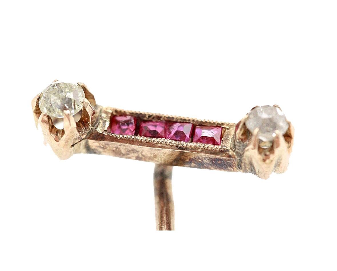 A Gentleman's 14 Kt yellow gold diamond & ruby stick pin, with four square cut rubies flanked by two diamonds..
Unmarked but tests as 14 Kt gold
All our stick pins are sold with a modern 9 Karat gold plated safety stop.