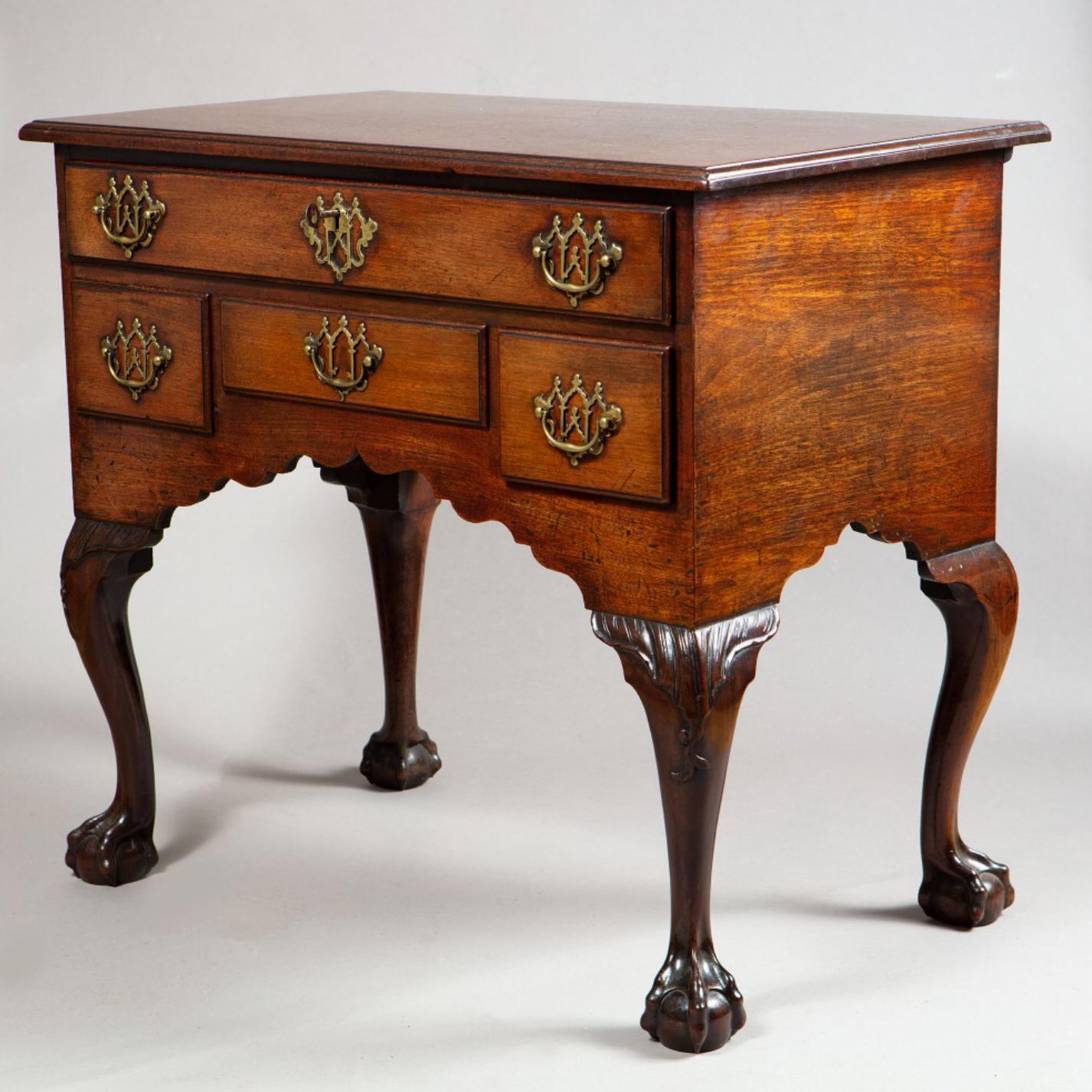 A distinctive and unusual early 18th century George I oak lowboy, the thumb moulded top above one long and three short drawers with pierced brass handles of Gothic design, the ornamental apron with ogee cut detail, the whole raised on ball and claw