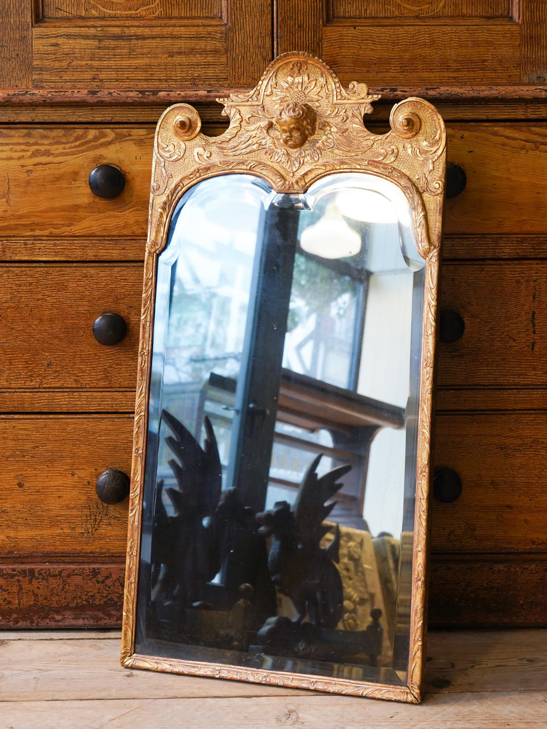 The carved pine frame has a central winged Putti mask surrounded by flower heads with tight scrolls above, the original twin arched bevelled mercury plate is in remarkable condition with only light foxing.

English, circa 1720. 

John Belchier
