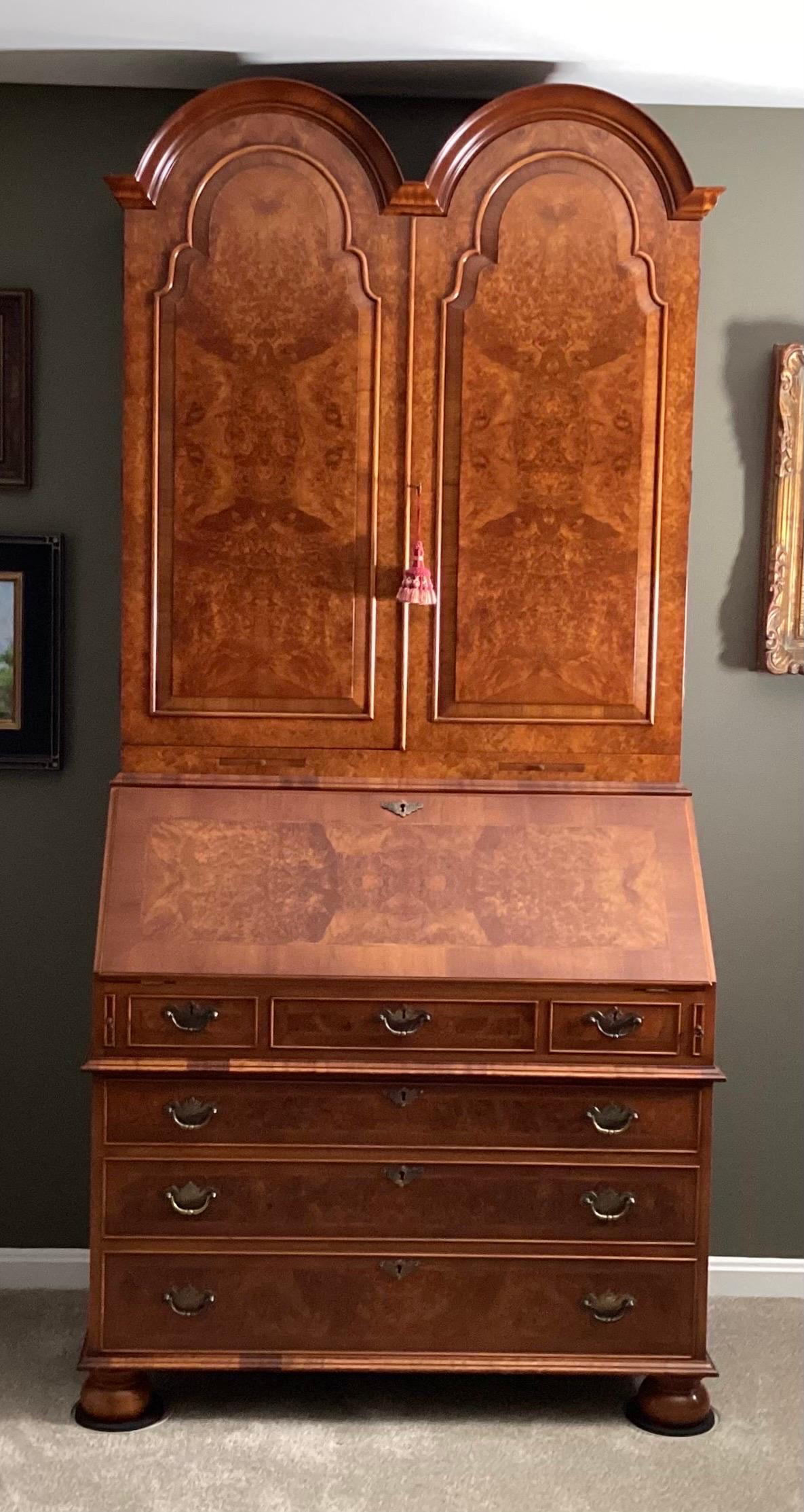 A beautifully detailed and well appointed Georgian style secretary desk, made in England.  The dovetailed drawers with brass hardware with a leather fall front section above the drawers, the top with highly figurative burl blind doors.  The desk is