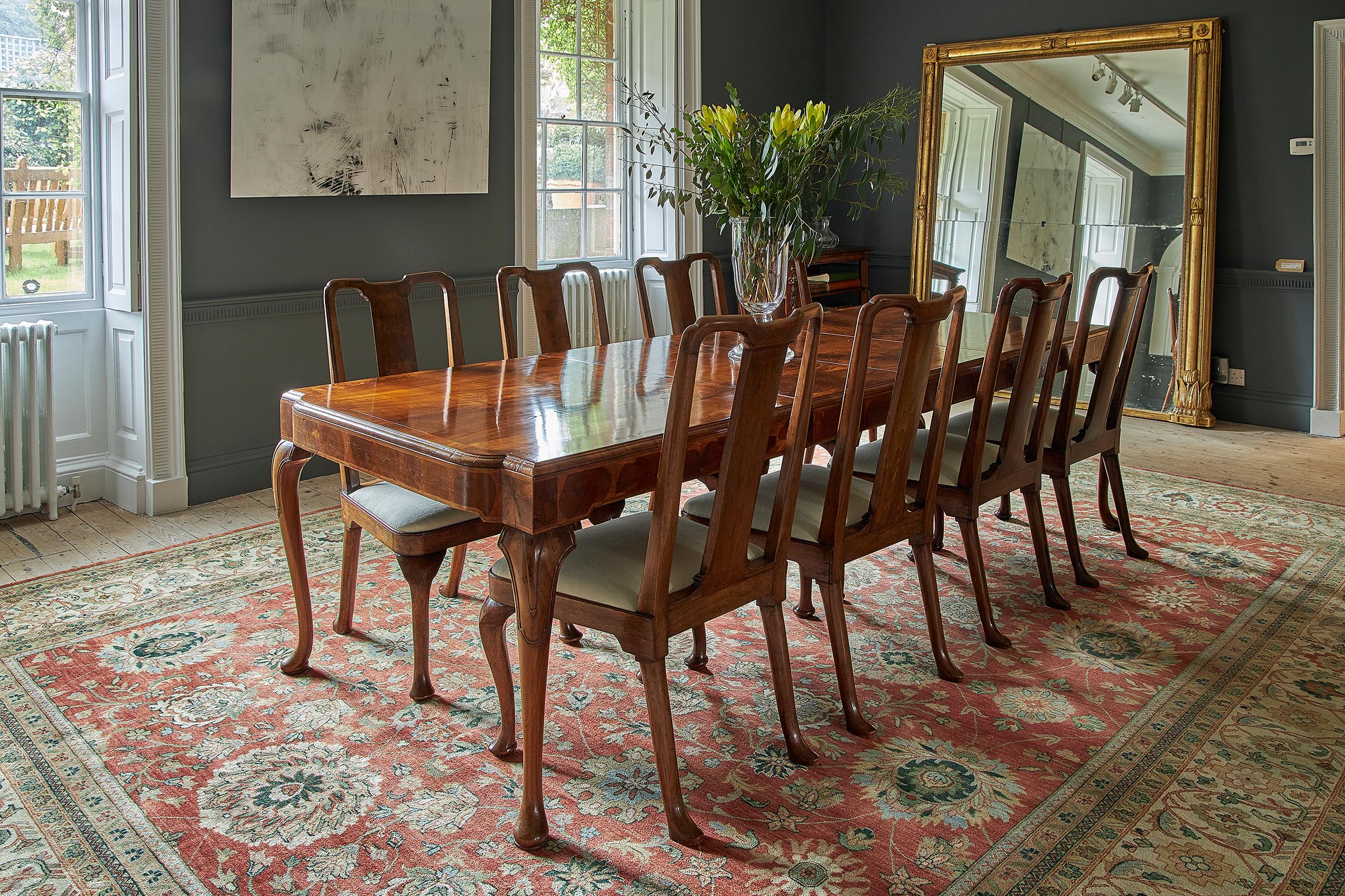 A George I style walnut veneer extending dining table and set of twelve dining chairs by Whytock & Reid, circa 1920s. The dining table with a cross-banded top, moulded edge and shaped ends having a yew wood oyster veneered frieze on hipped cabriole