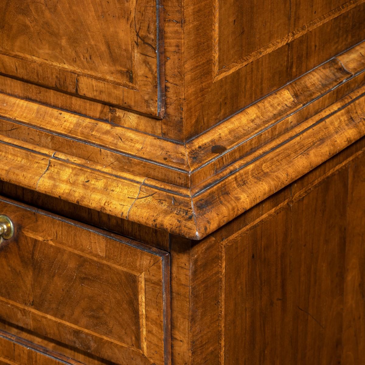 A George I walnut tallboy, of tall rectangular form, the upper section with a moulded cornice over two short and three long drawers, and the base with two short and two long drawers, all with flame veneered panels within crossbanding and inlaid