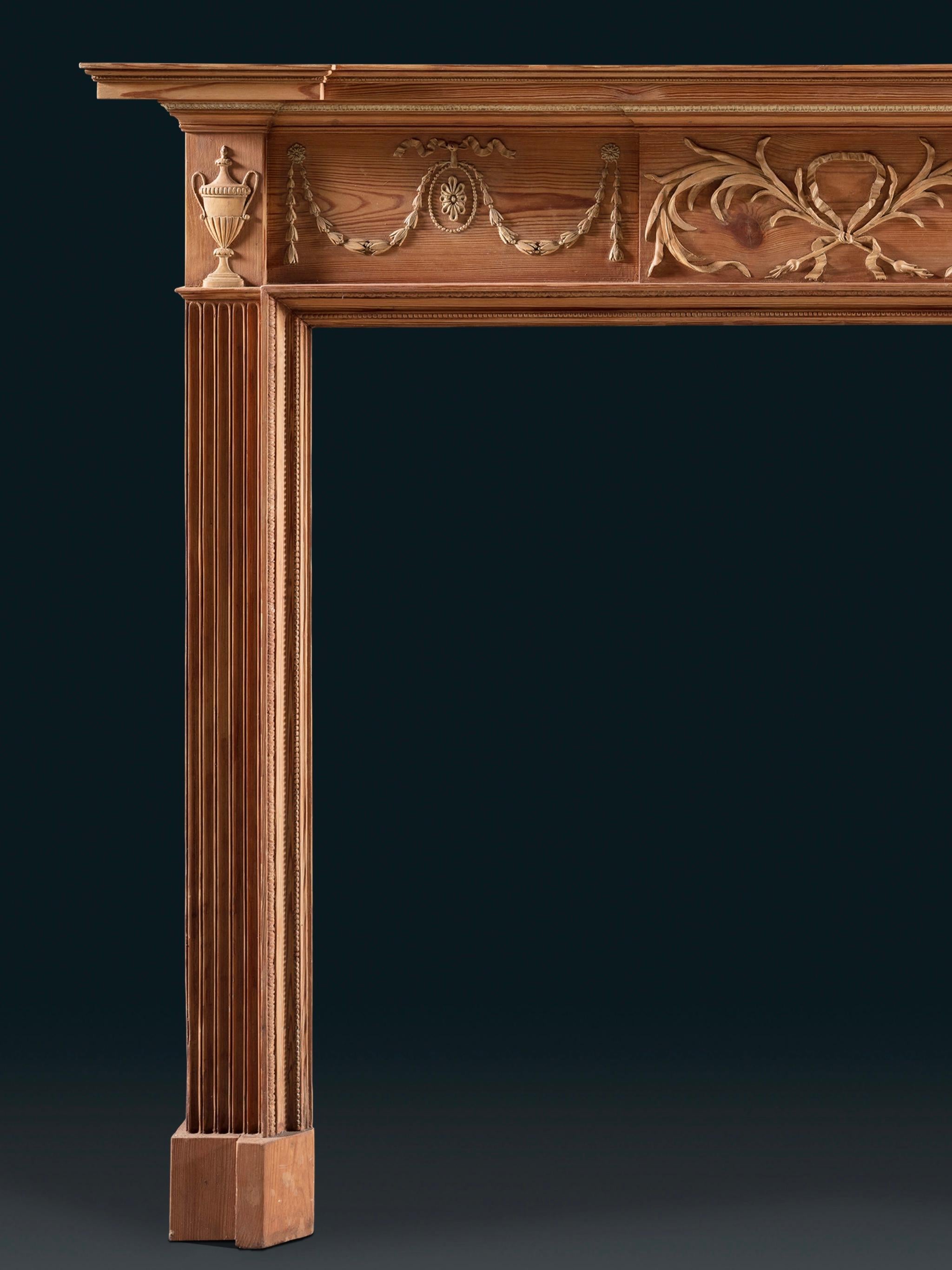 Une cheminée de bonnes proportions néoclassiques avec des blocs de pied en cannelure et des jambages cannelés. Sur la tablette centrale se trouvent deux oignons, liés par un ruban, leurs formes organiques bien sculptées. Des guirlandes de feuillage,