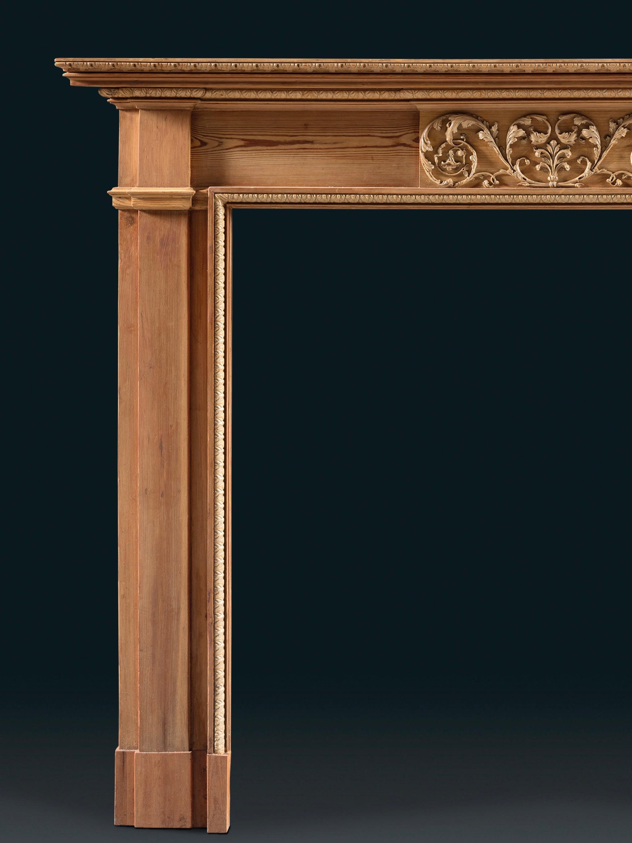 En grande partie non sculptée, cette cheminée en pin et gesso est de forme néoclassique et de teinte austère. Une moulure de feuilles d'eau en gesso encadre l'ouverture et la tablette centrale présente une Bower de volutes d'acanthe en ébullition,