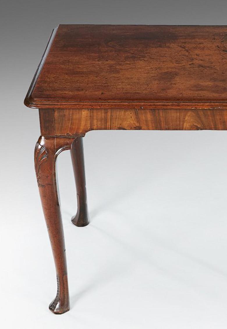 A George II Irish walnut side table. A rare and untouched George II Irish walnut side table, the rectangular top with a moulded edge, above a shaped frieze, resting on scallop shell cabriole legs, terminating in a faceted foot, exceptional color and