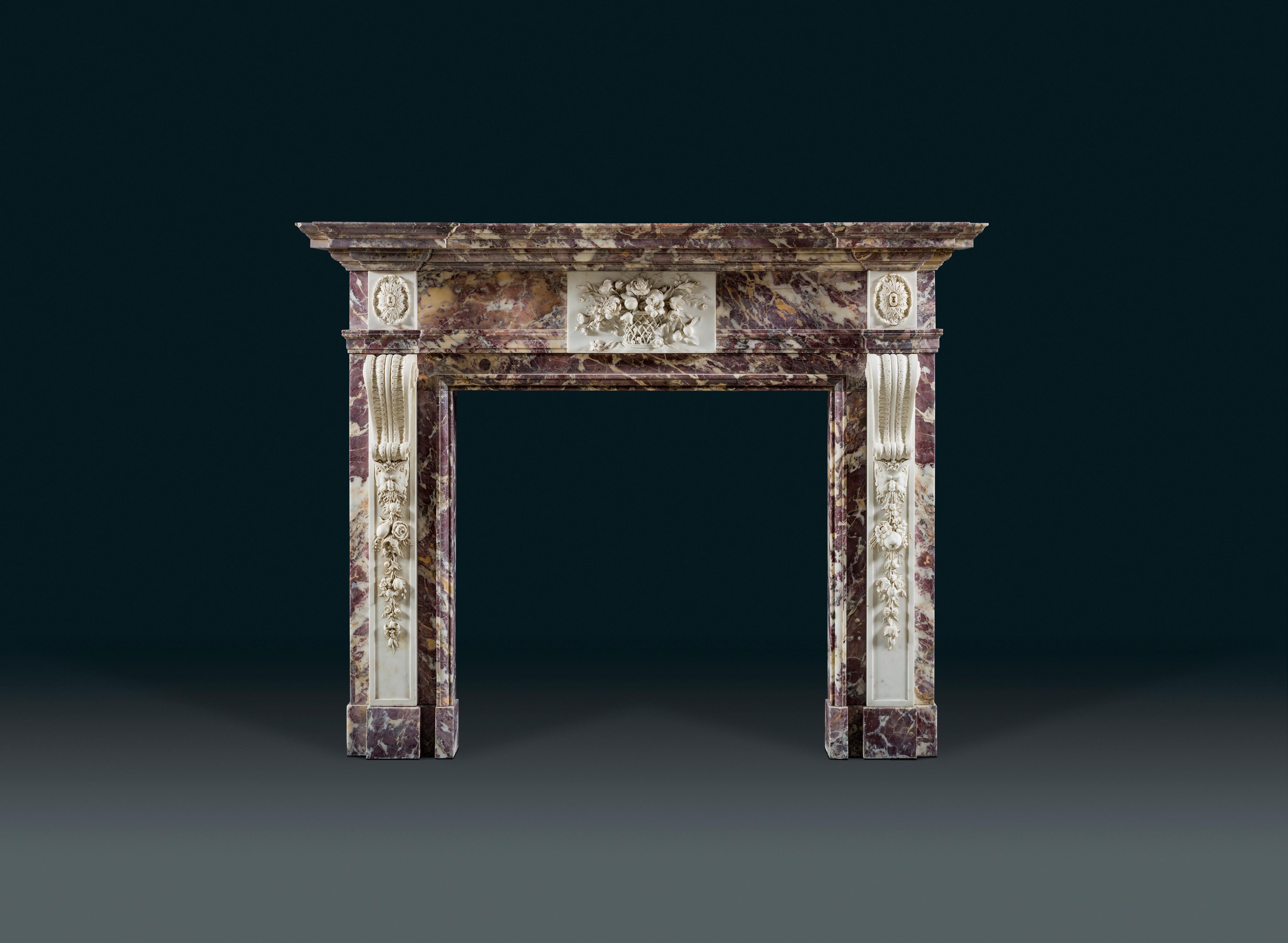 A rare and unusual George II, Palladian fireplace in variegated Breccia Violette marble decorated in contrasting statuary marble. The exceptionally fine naturalistically carved centre tablet bared a basket of fruits and flowers, attributes of spring
