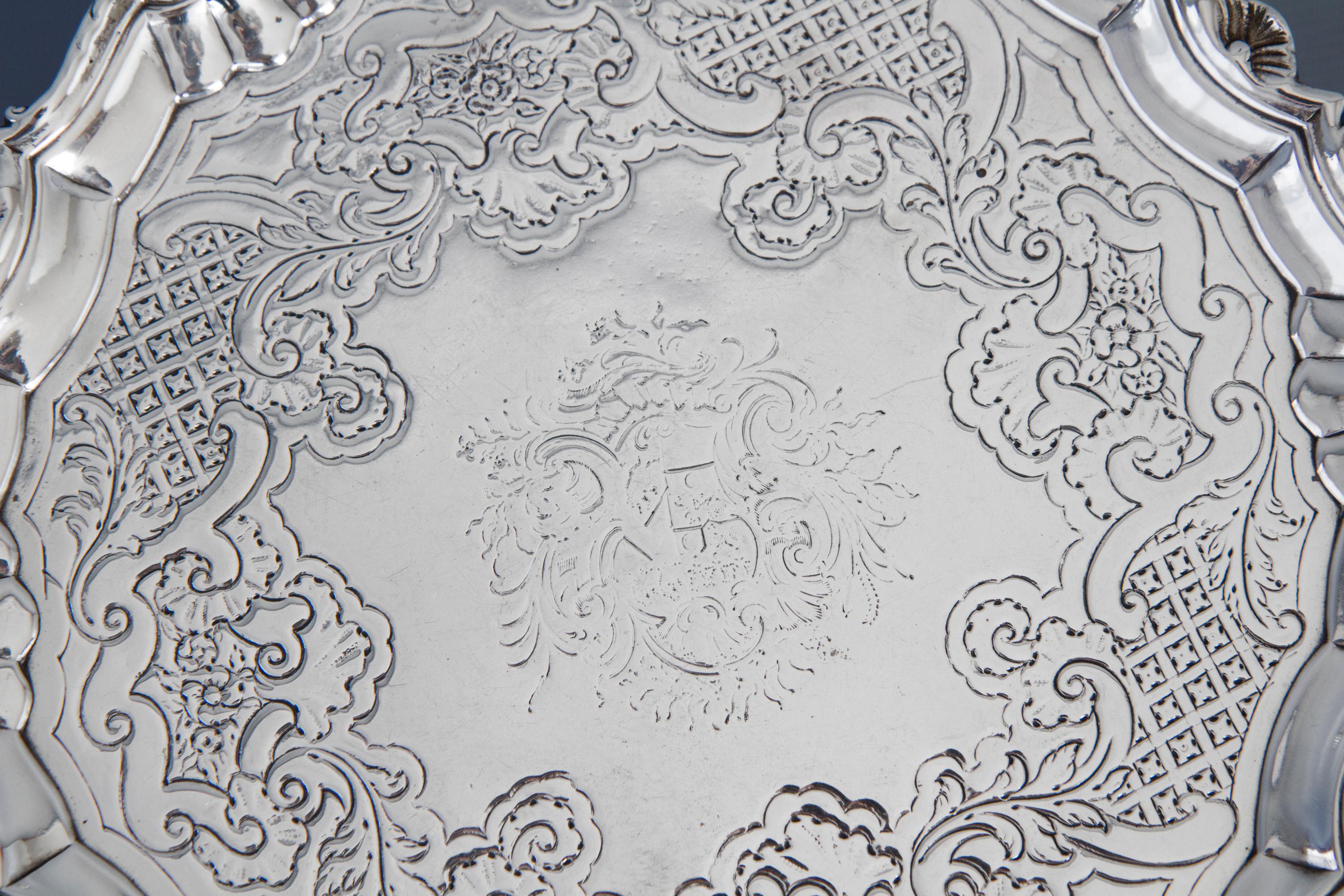 An early Georgian silver salver of shaped circular form. The rim with shell decoration and the central plate engraved with floral arabesques about a central crest. The whole standing on three scrolling hoof feet.
 
Marked to the underside for