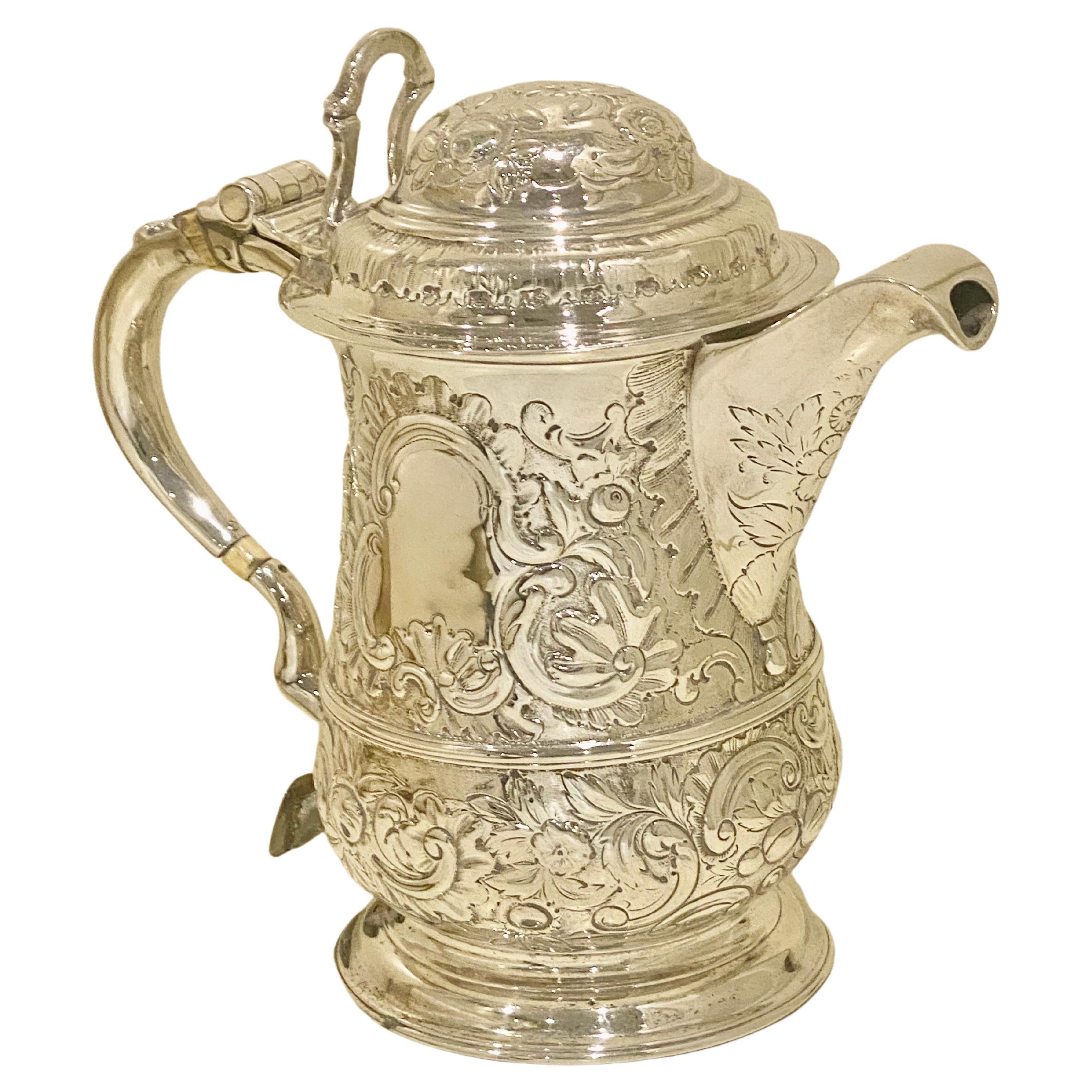 A fine quality chased silver Georgian quart tankard embellished with beautiful floral and shell motifs which is magnificently set on a matt background and highlighted with scallop surrounds. The hinged domed lid has a beautiful chair back