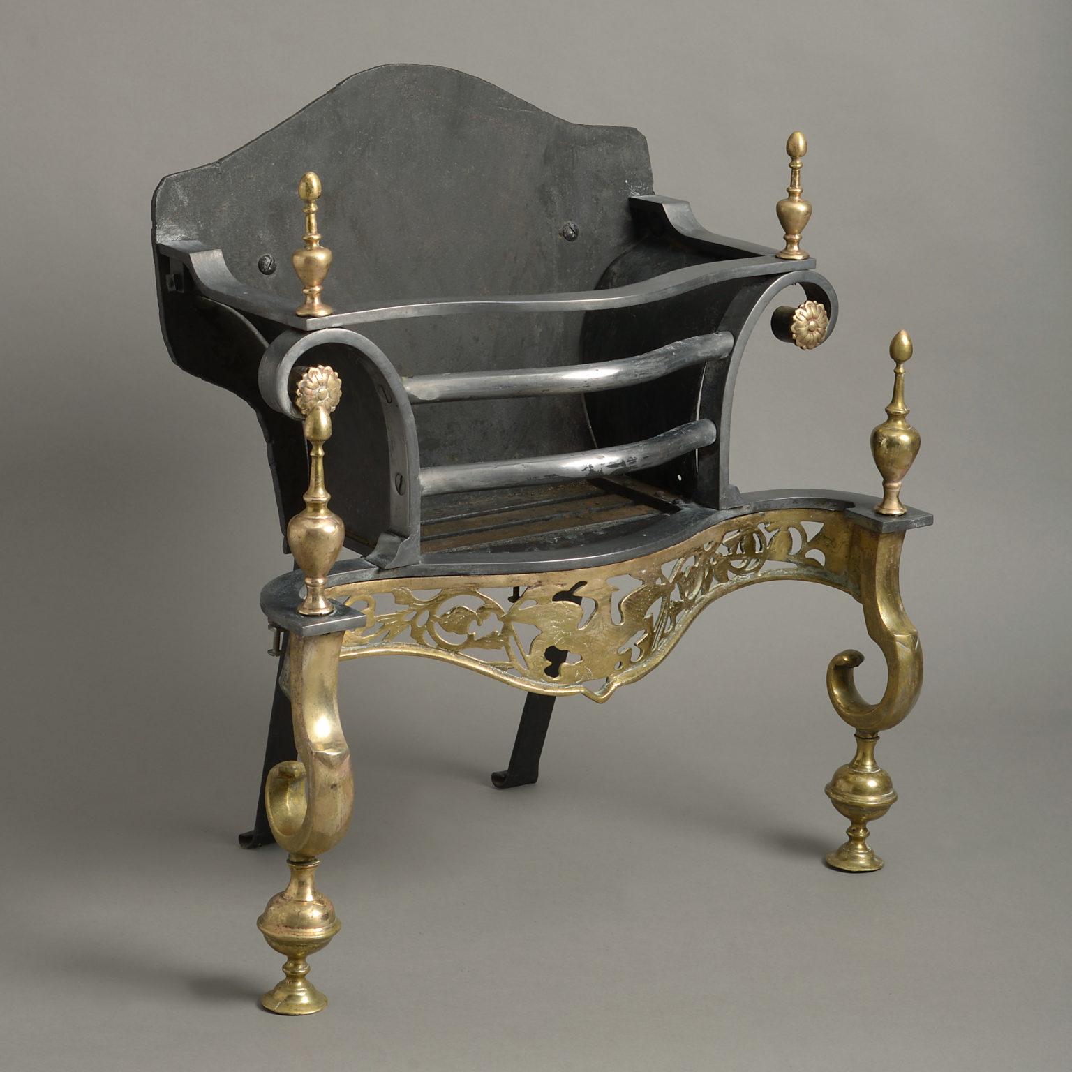 An early 20th century Edwardian period brass and steel fire basket in the George II manner, of serpentine form, having urn finials, a shaped and pierced frieze and supported upon scrolling legs.