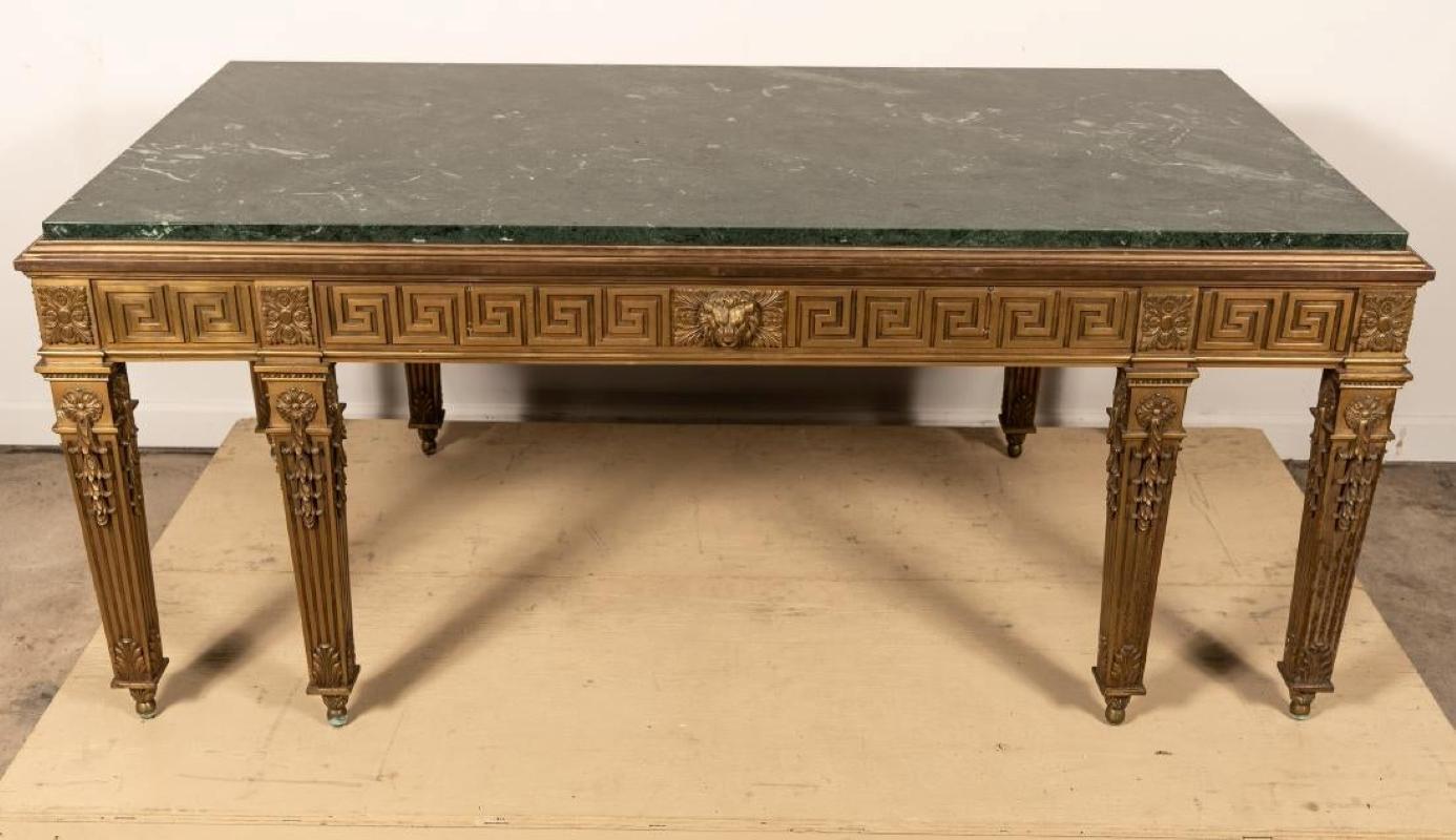 Manner of William Kent, Continental, 20th century. A George II style marble top and gilt bronze library or dining table having a Greek key frieze centered with a mask on eight square tapered and fluted legs headed with patera blocks. Measures: