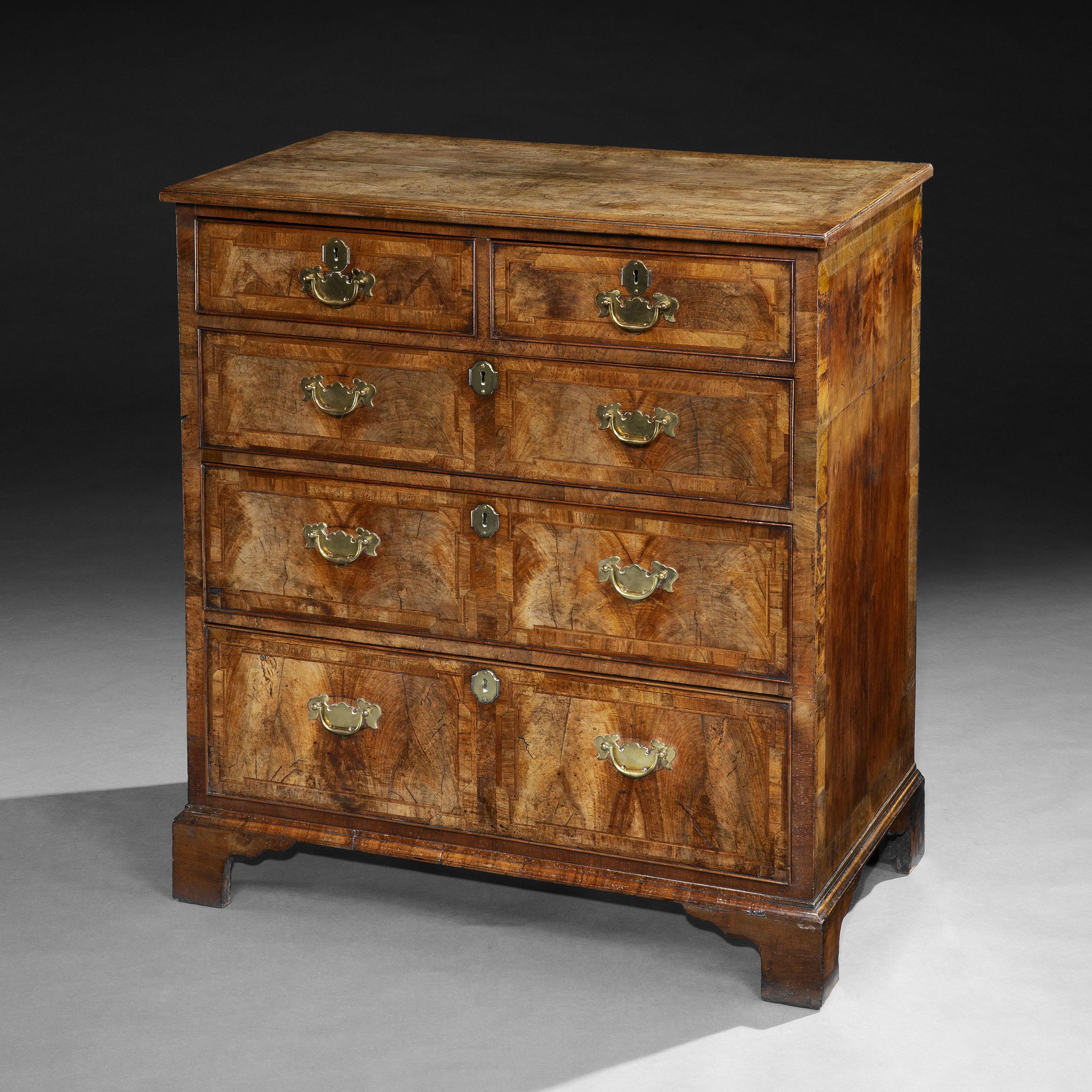 English, circa 1720.

A very fine early eighteenth century walnut chest of drawers of exceptional colour and patination, with quarter veneered top and re-entrant corners. Two small draws sit above three large draws, all raised on bracket