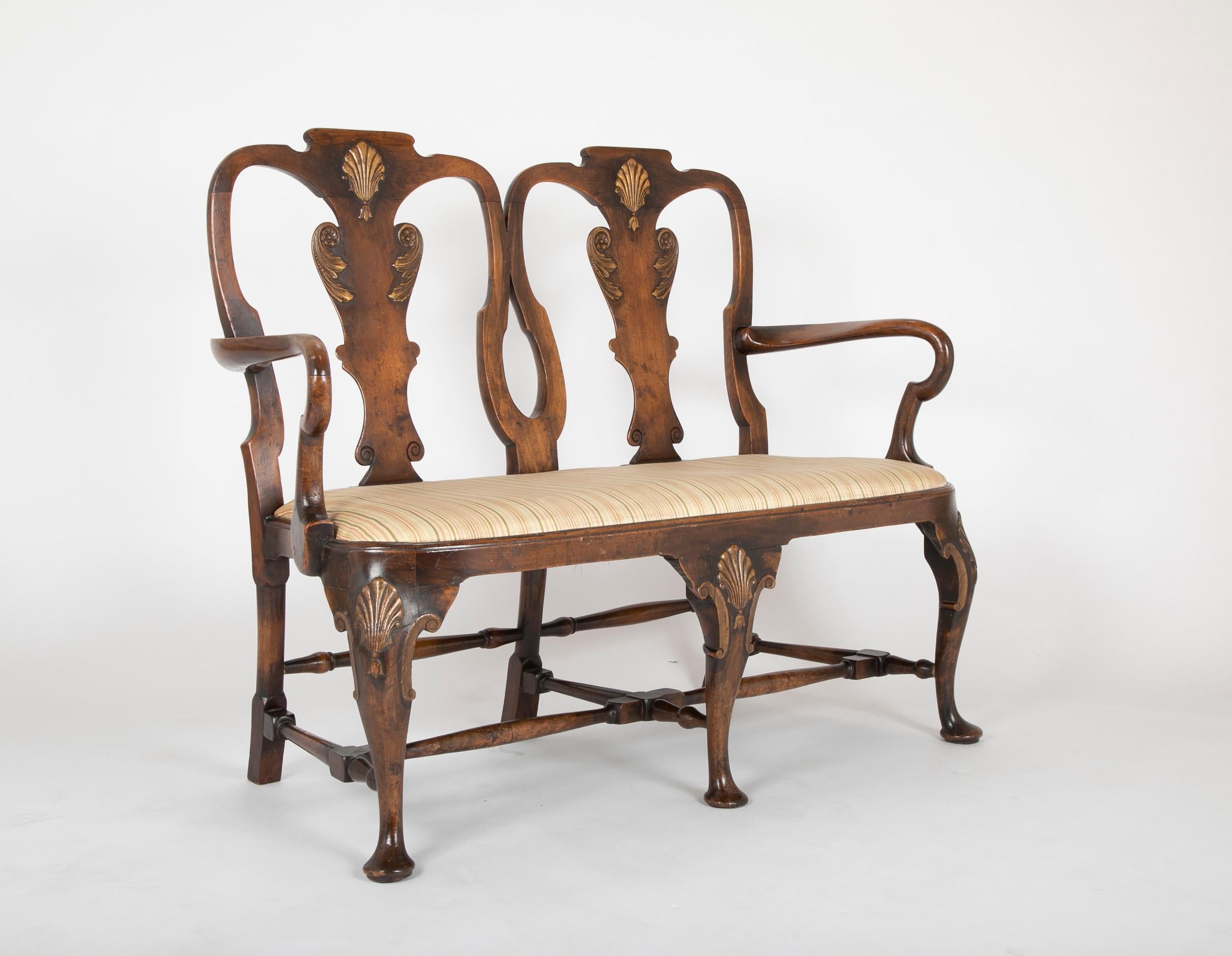 A George II walnut two chair back settee with gilt shell knees & splats, shepherds crook arms and stretcher base with original drop in seat of compass form. Early to Mid 19th Century.