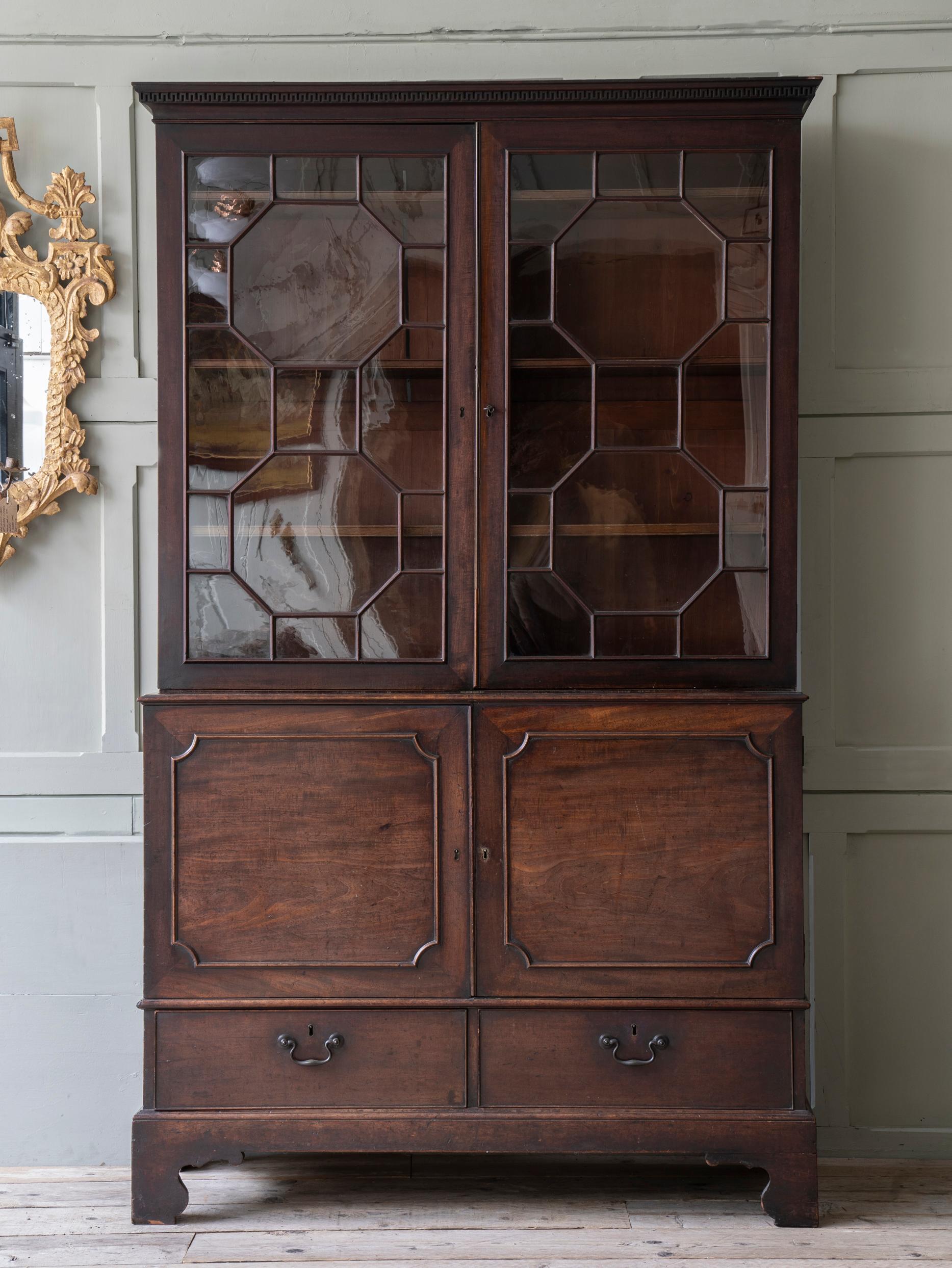 The cupboard base with lower, drawers raised on bracket feet, the astragal glazed double doors having adjustable shelves behind.

An astoundingly original piece, the surface retaining its original oil wax finish.

All of the mouth blown glass