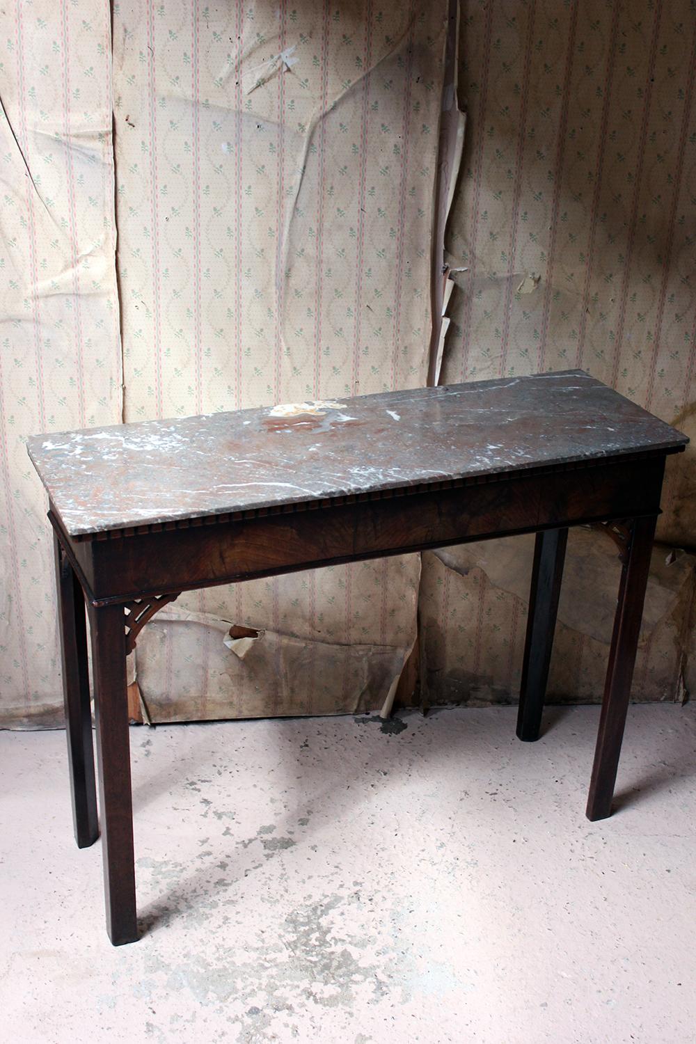 The principally Georgian mahogany side or hall table, having a later portasanta marble top and applied dentil frieze, decorated with blind fretwork on chamfered block legs, the elegant and slim proportioned carcass with good color, surviving from