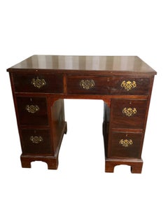 A George III crossbanded mahogany kneehole desk of seven drawers with gilt handl