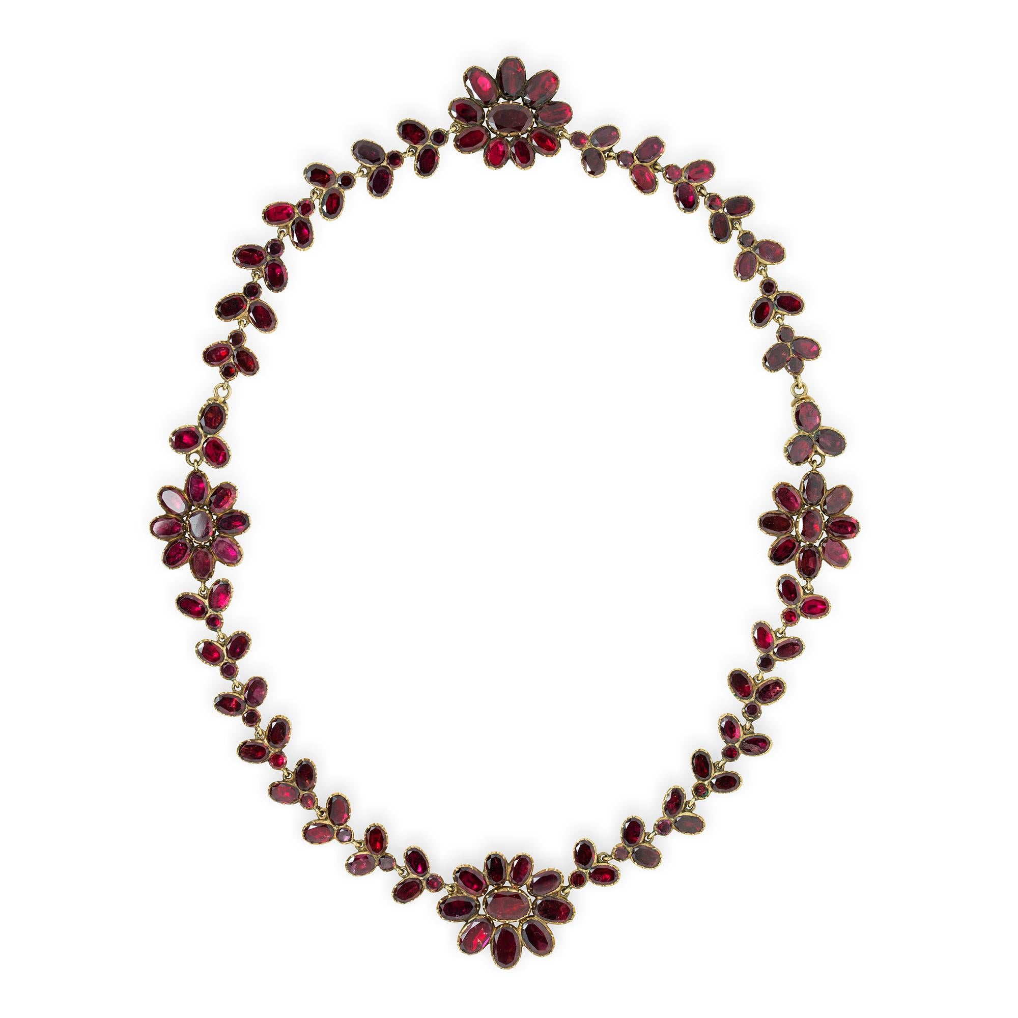 A George III garnet-set demi-parure, the necklace consisting of four garnet-set foliate clusters linked with articulated garnet-set trefoil-links, 17.5 inches long, the bracelet consisting of seventeen articulated garnet-set trefoil-links 7 inches