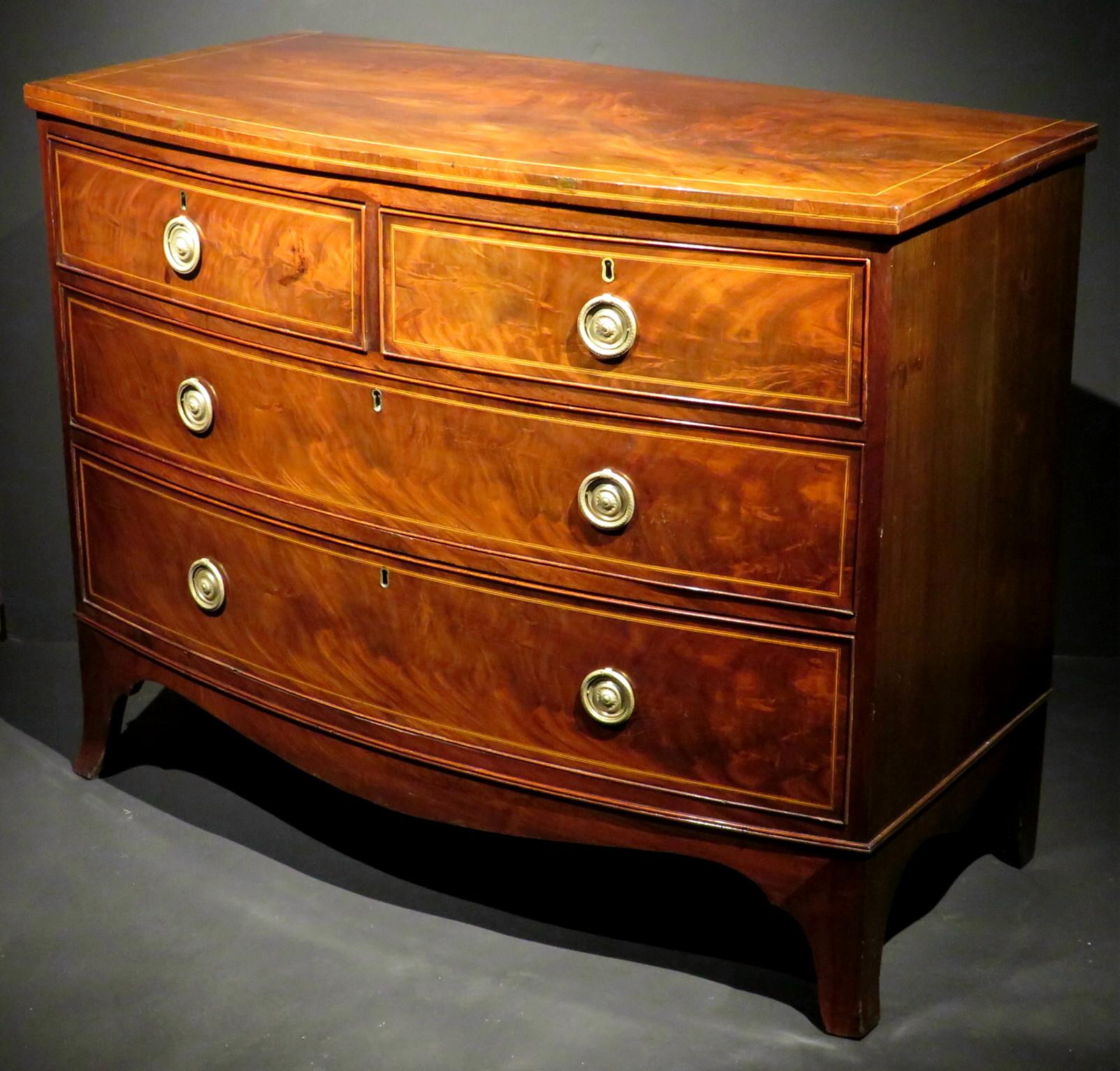 A very handsome bow-fronted Georgian chest of drawers in mahogany, exhibiting exceptional colour and grain,  as well as being of fine and accommodating proportions. The richly figured case showing a satinwood strung top over 2 short drawers, above