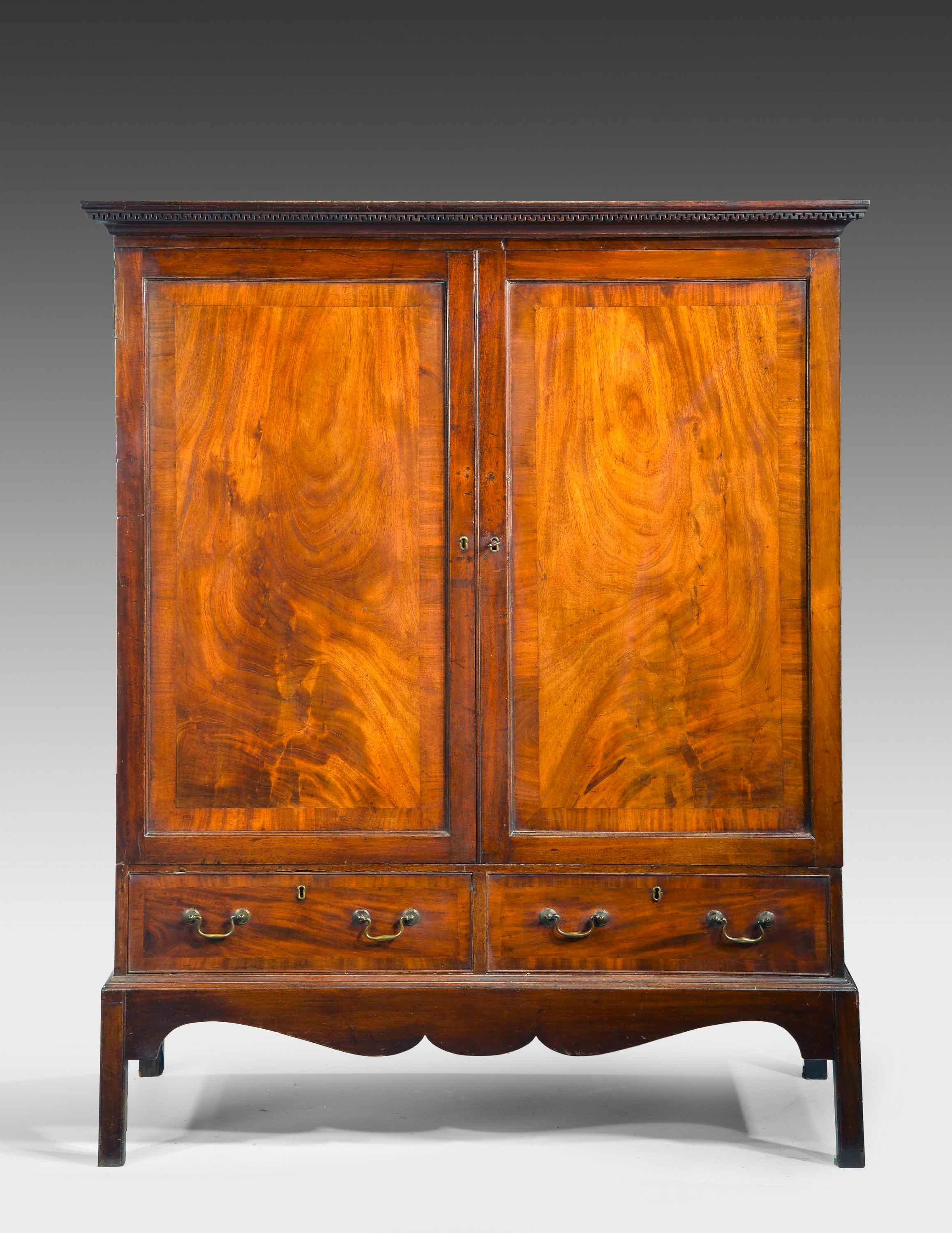 A George III Irish mahogany press. The doors crossbanded in well figured timbers. The top with a fine cornice. Two draws to the base section on square supports.