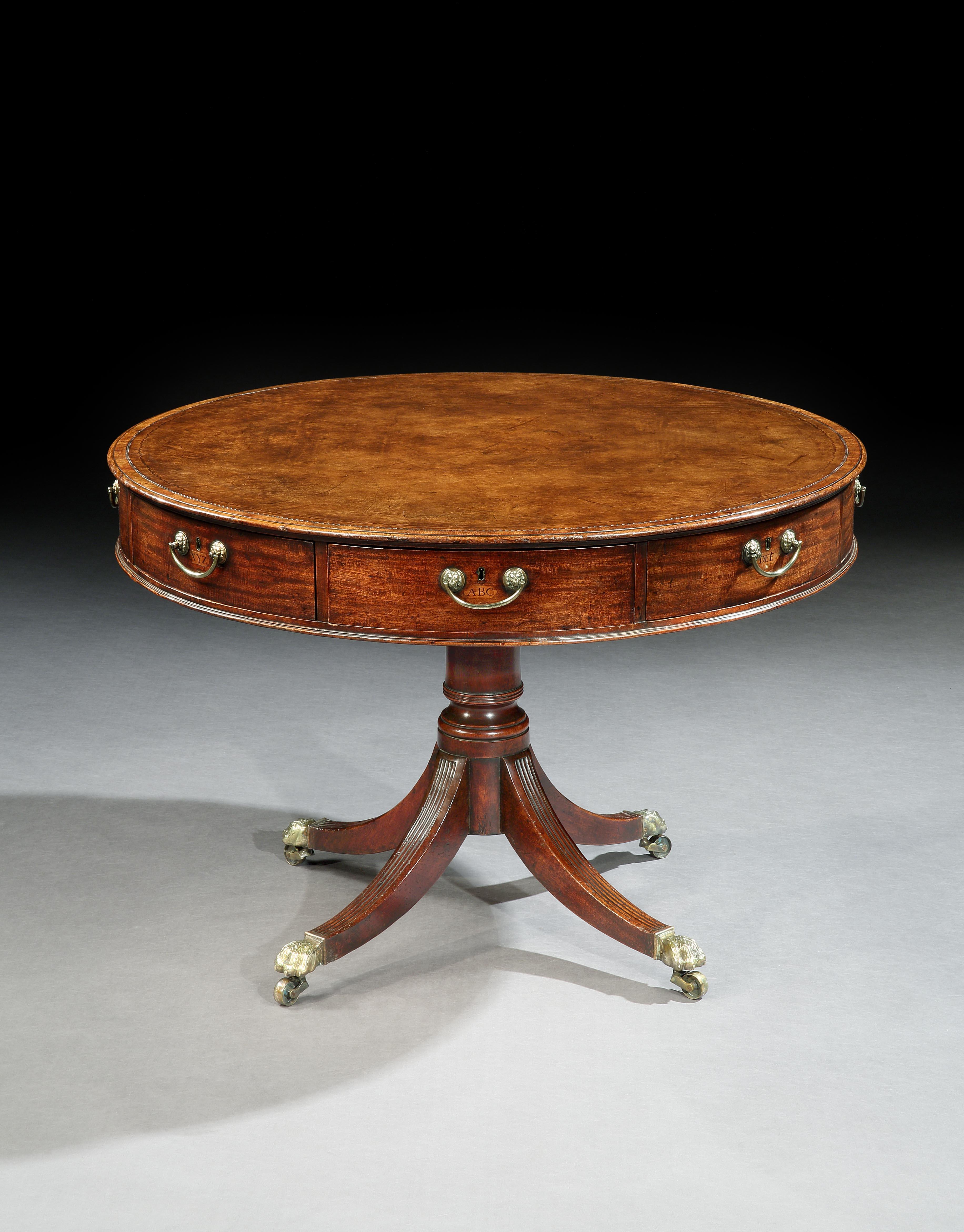 A quality George III mahogany circular revolving drum library or rent table. The top with an inset panel of tanned hide, fitted with 8 drawers inlaid with the letters of the alphabet all retaining the original brass lions head loop handles. The