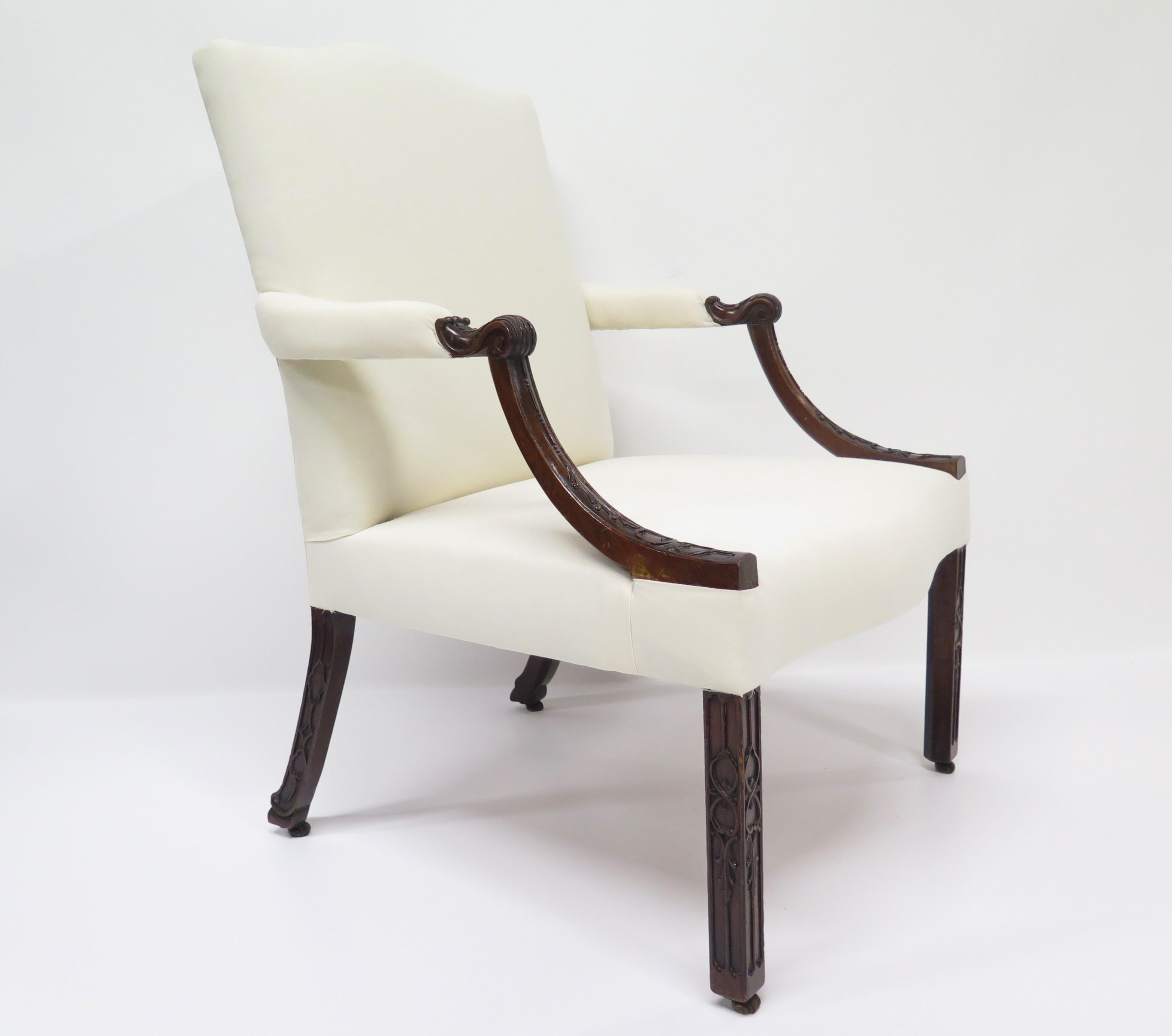 George III mahogany Gainsborough library chair in the Manner of Thomas Chippendale, the rectangular padded back and seat are covered in muslin fabric, the partially padded arms and coiled acanthus handholds above down swept blind fretwork carved