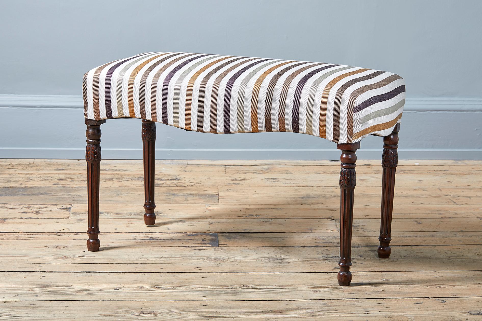 shaped rectangular seat above stiff leaf carved turned fluted legs, on turned feet, upholstered in Hermes Ottoman stripe design fabric.