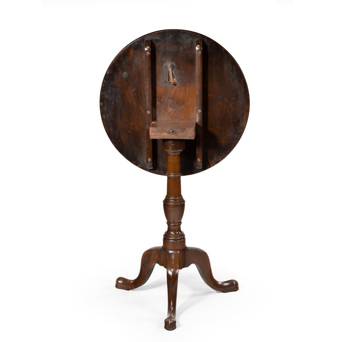 A George III mahogany tilt-top occasional table, the circular top made from a single piece, raised on a turned vase-shaped support. English, circa 1800.
  