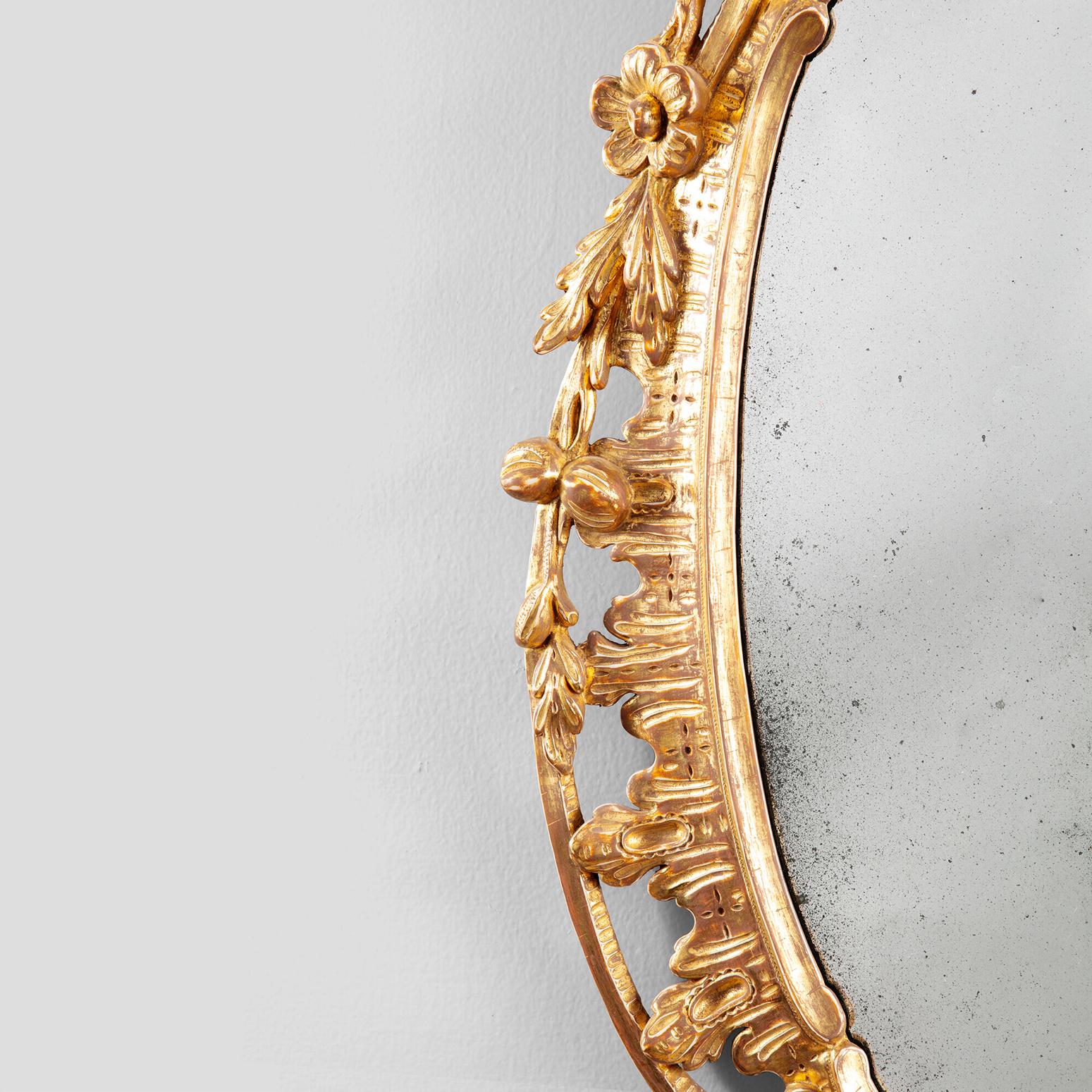 Un site  Miroir ovale Chippendale de style George III, vers 1770. Sculpté en pin, le miroir est décoré de rinceaux rococo en forme de C, de feuillages et de fleurs. Le cadre a été redoré mais conserve une plaque de miroir argentée de procédé ancien.