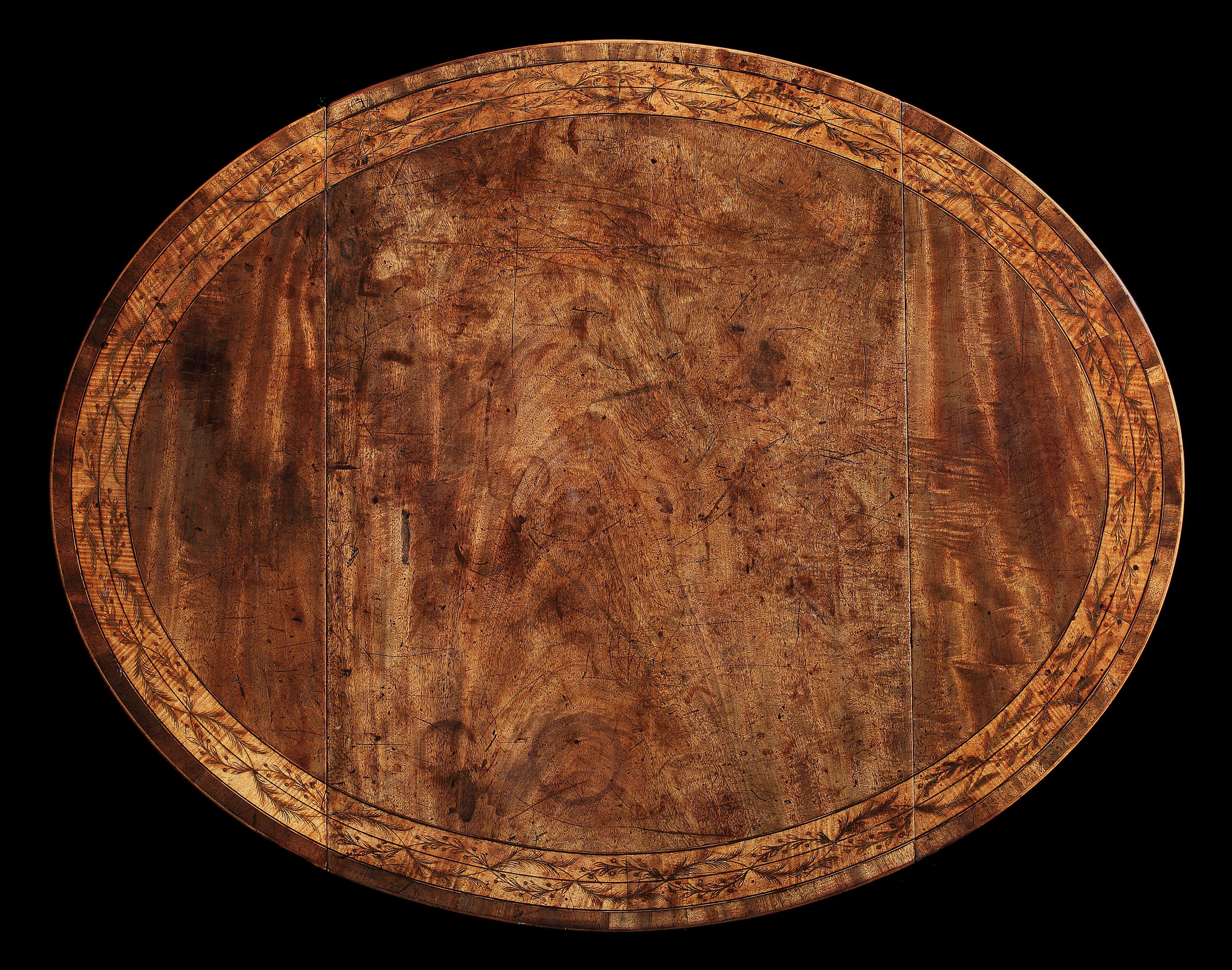 A Sheraton period oval Pembroke table in figured mahogany of a particularly Fine colour and patina.
The oval top crossbanded and with an inset banding of intertwined floral branches on a satinwood ground.
The frieze fitted with a drawer flanked by