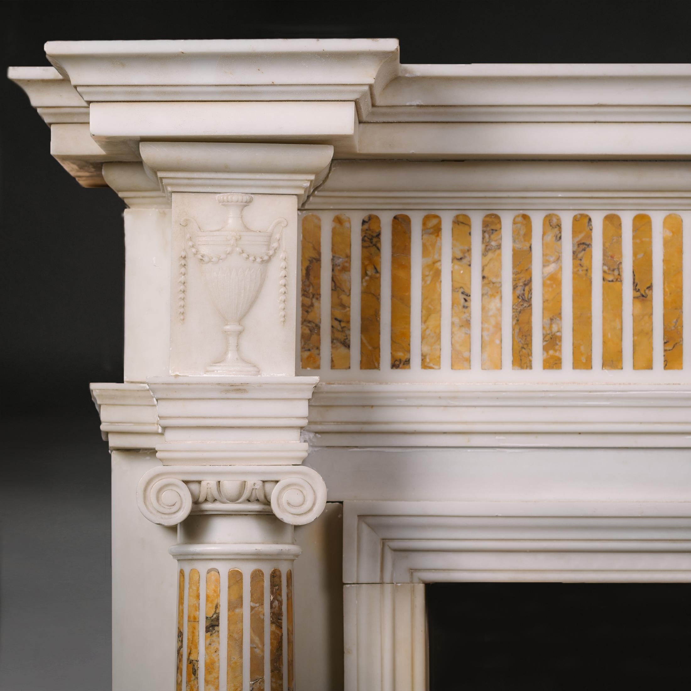 A George III Period carrara marble and sienna marble chimney piece.

This delicately carved a beautifully detailed fireplace has a breakfront shelf with inverted moulded edge. The frieze is inset with Siena marble flutes. The central projecting